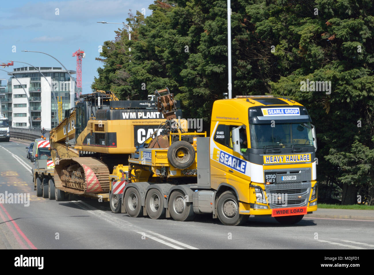 A Searle Group Volvo FH16 tractor unit towing a Nooteboom low-loader trailer carrying a W M Plant Hire Caterpillar CAT 345C long-reach excavator Stock Photo