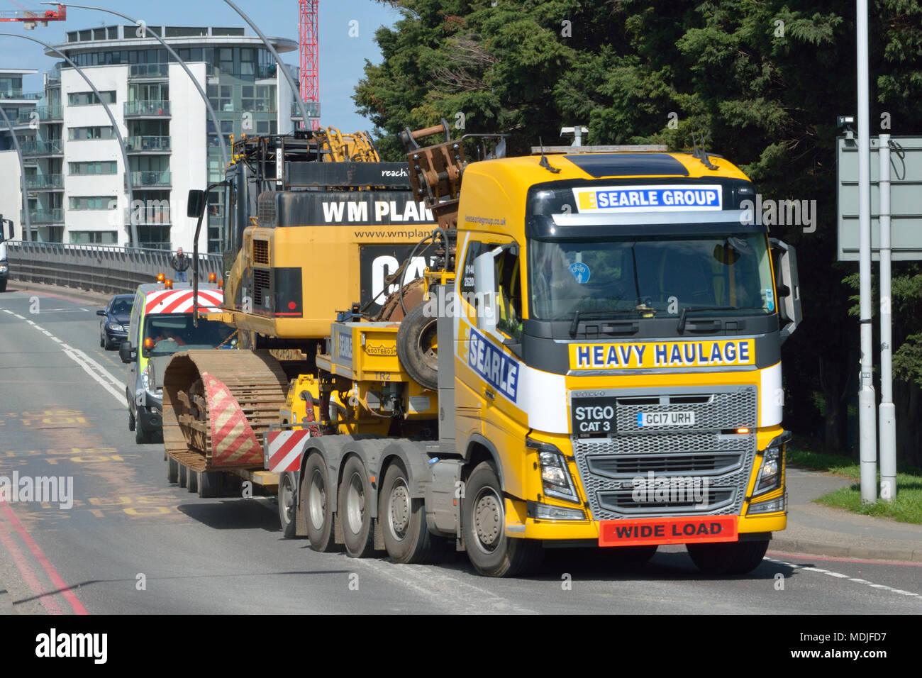 A Searle Group Volvo FH16 tractor unit towing a Nooteboom low-loader trailer carrying a W M Plant Hire Caterpillar CAT 345C long-reach excavator Stock Photo