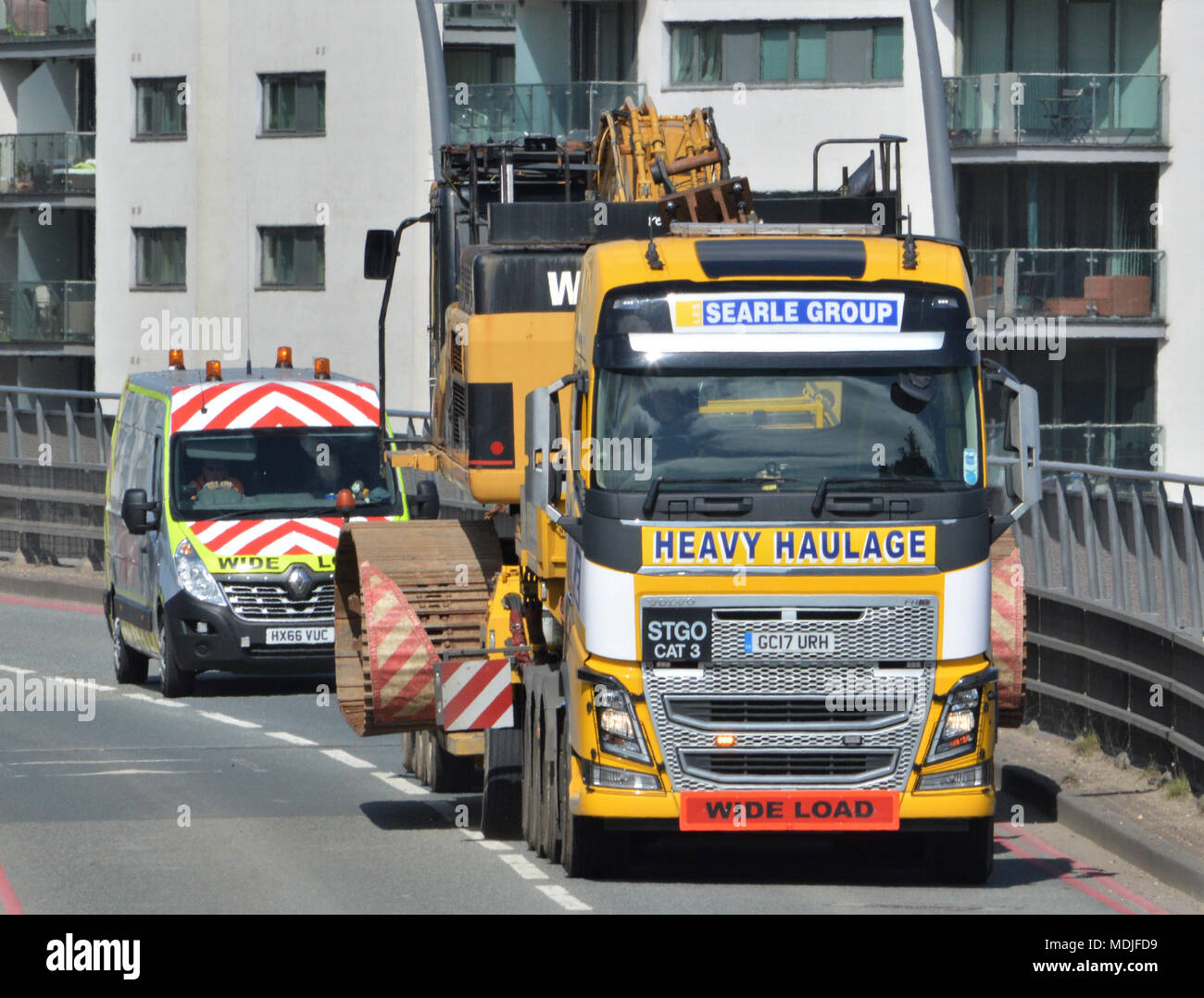 A Searle Group Volvo FH16 tractor unit towing a Nooteboom low-loader trailer carrying a W M Plant Hire Caterpillar CAT 345C long-reach excavator Stock Photo
