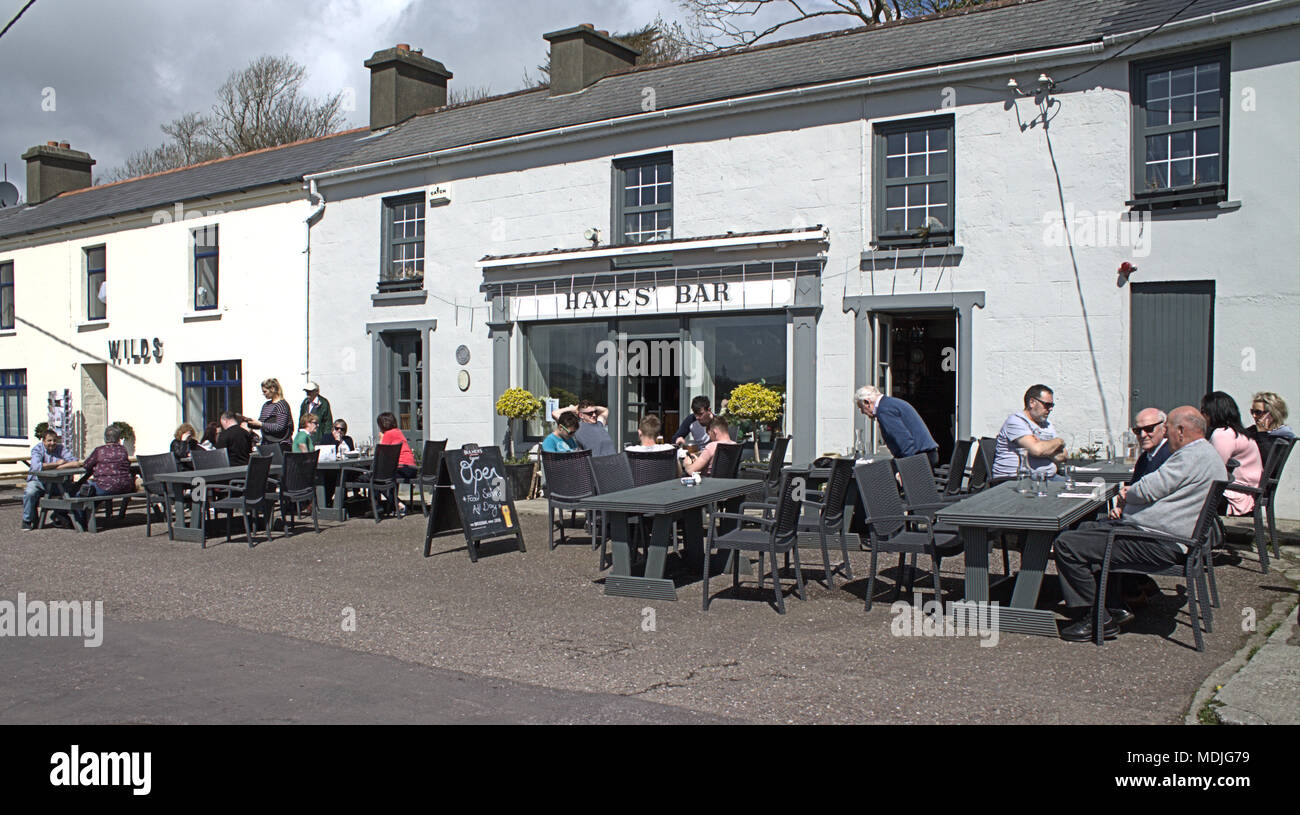 holiday makers and local people enjoying the food and drink outdoors in the sunshine at glandores restaurants, a popular irish tourist resort. Stock Photo
