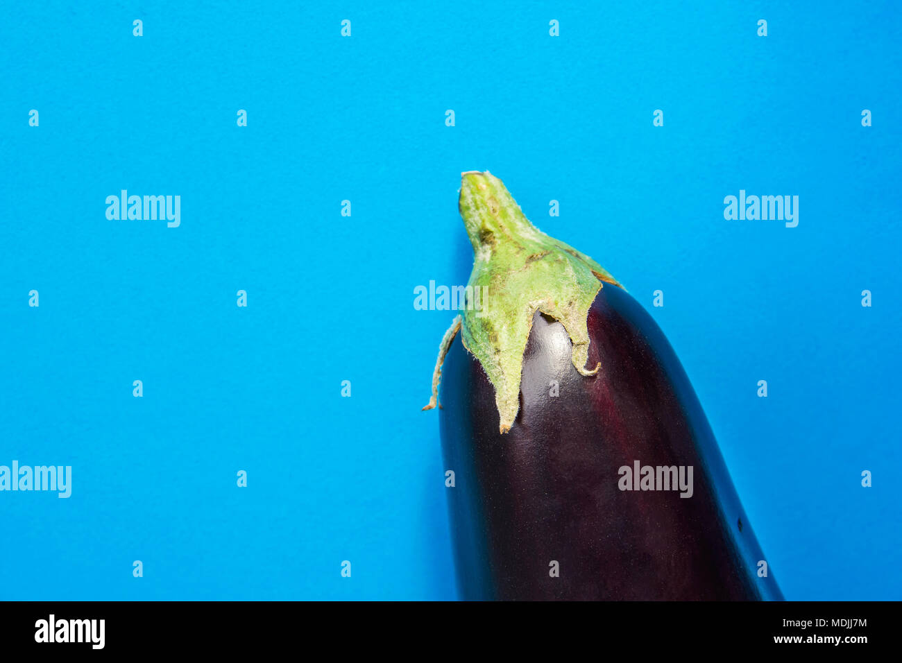 Single Ripe Organic Whole Eggplant with Green Calyx on Blue Background. Vitamins Healthy Diet Summer Autumn Superfoods Concept. Mediterranean Cuisine. Stock Photo