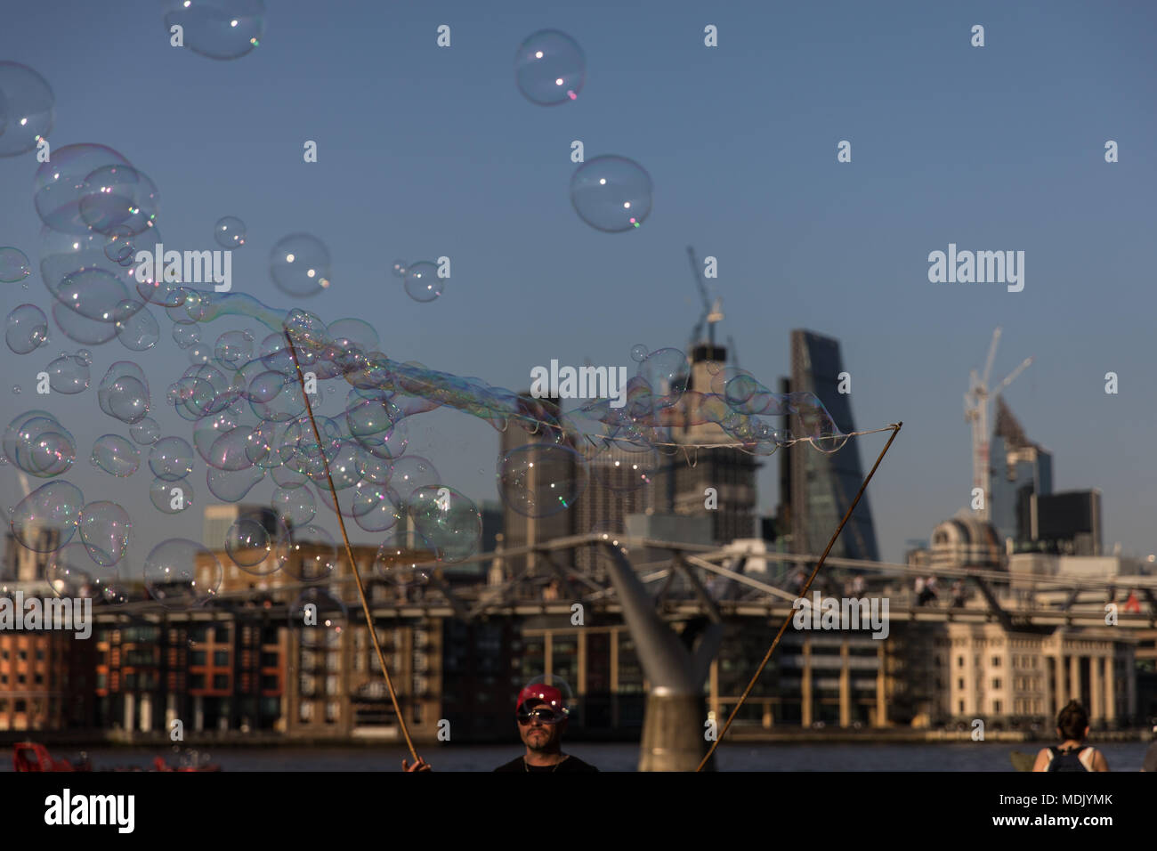 London, UK. 19th April, 2018. UK Weather: A busker makes bubbles for passers by on the southbank of the Thames during a beautiful evening in London, UK Credit: Carol Moir Stock Photo