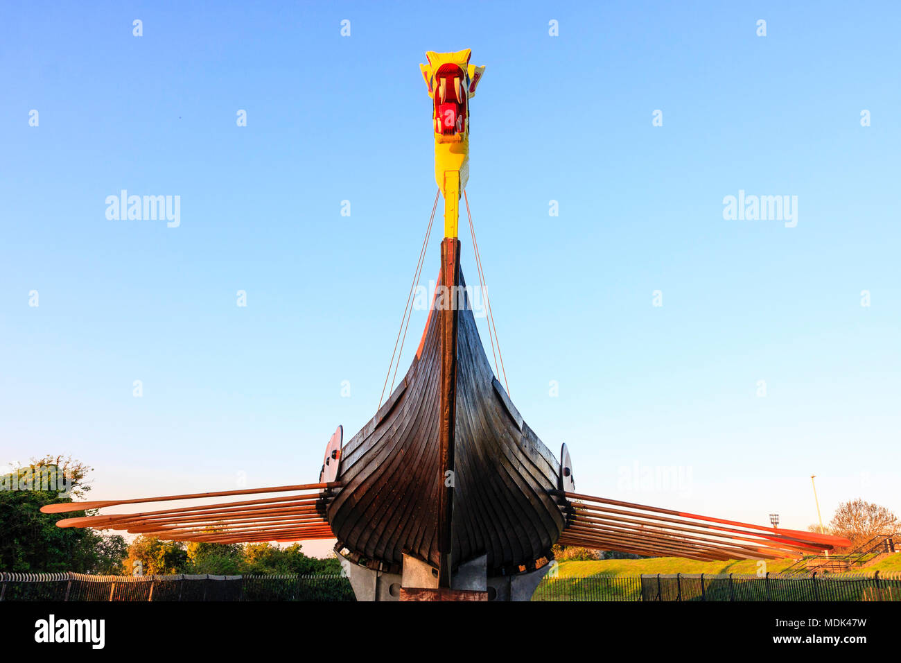 The Hugin, re-constructed Viking Ship on stand at Pegwell, Ramsgate. Lit up by sunrise light during the golden hour. Blue sky background. Stock Photo