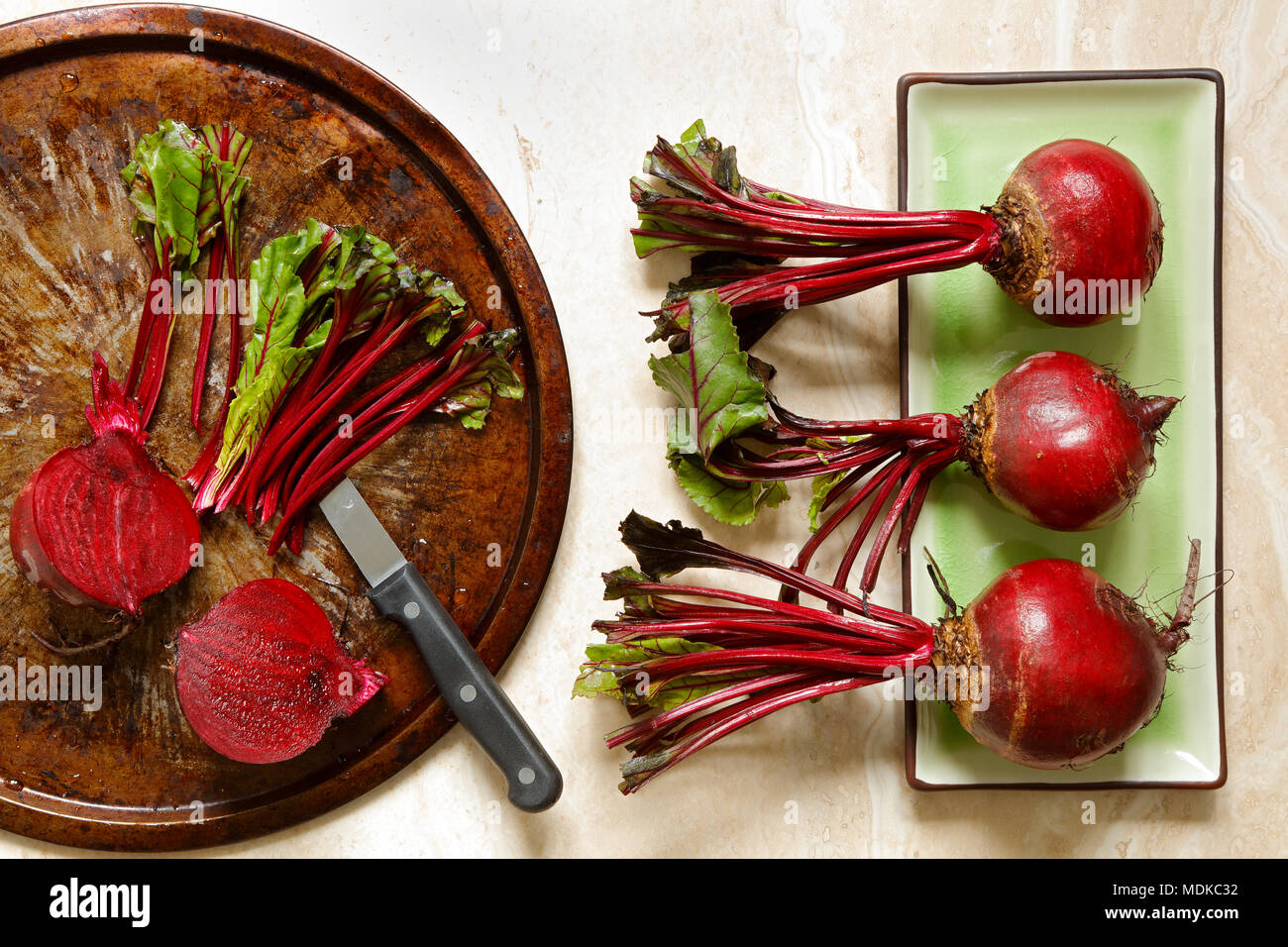 Fresh beetroots on green ceraminc tray and metal plate with knife on marble with copy space to right Stock Photo