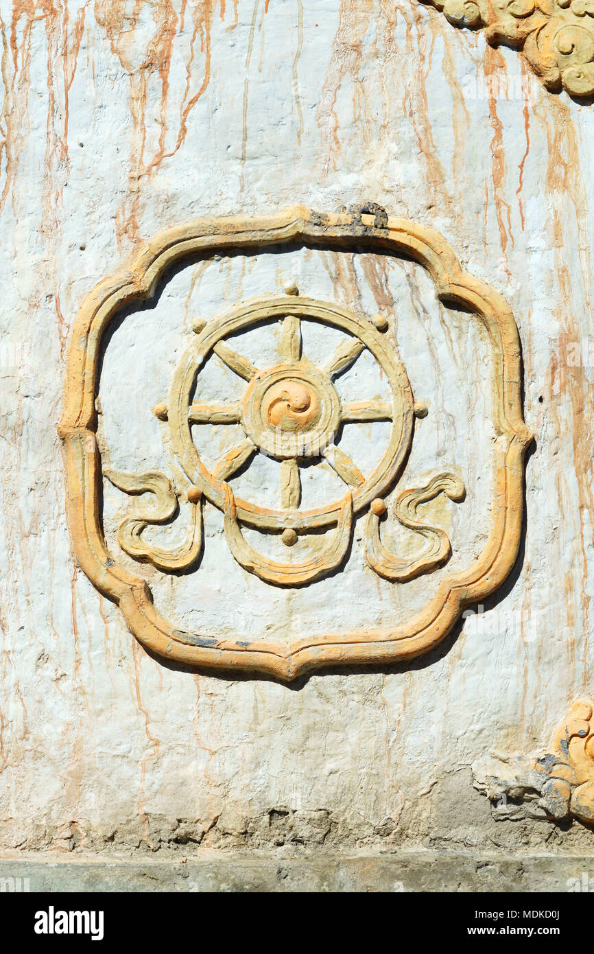 Painted dharma wheel buddhist symbol, carved on the entry chorten leading to the village of Ghemi, Upper Mustang region, Nepal. Stock Photo