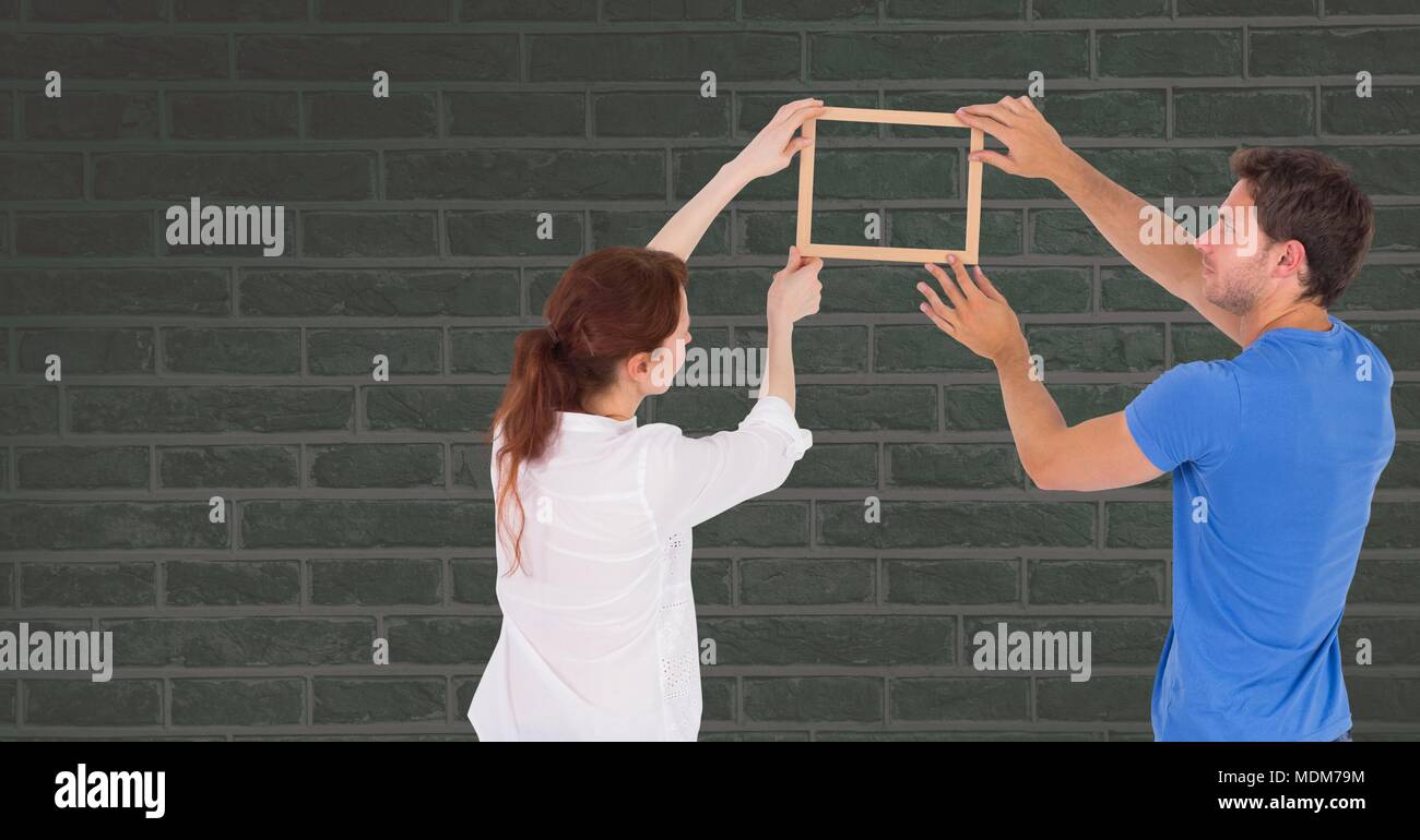 Couple holding picture frame against wall Stock Photo