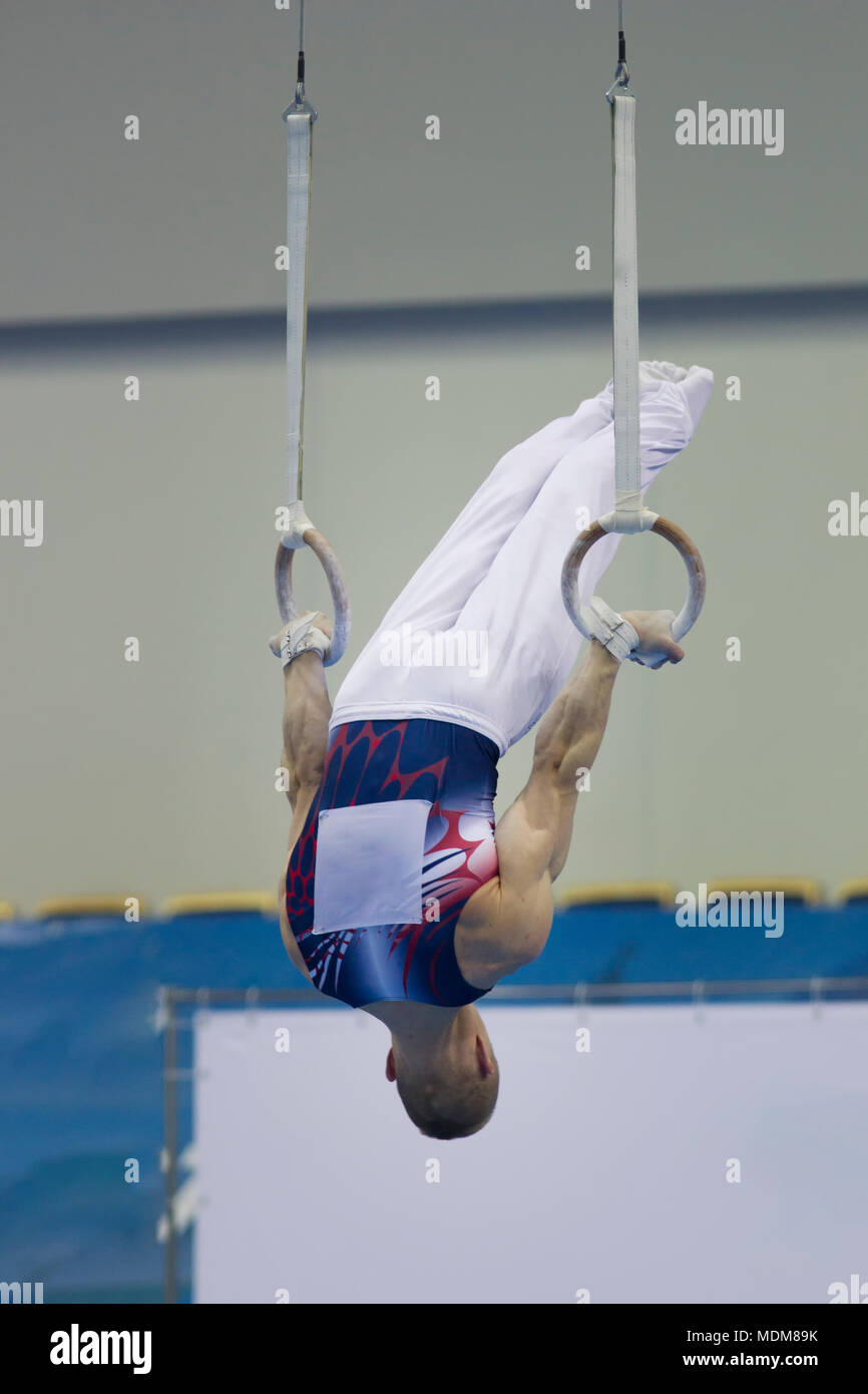 young-athletic-man-upside-down-on-gymnastic-rings-at-the-championship-close-up-MDM89K.jpg