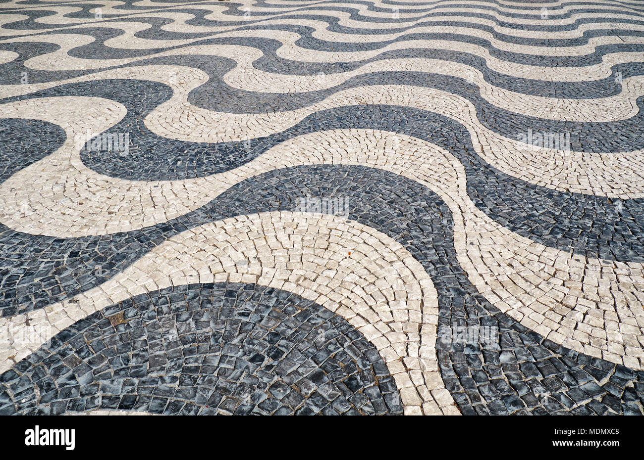 The wave shape pattern of tradition Portuguese pavement mosaic designed with black and white stones of basalt and limestone on the Rossio square. Lisb Stock Photo