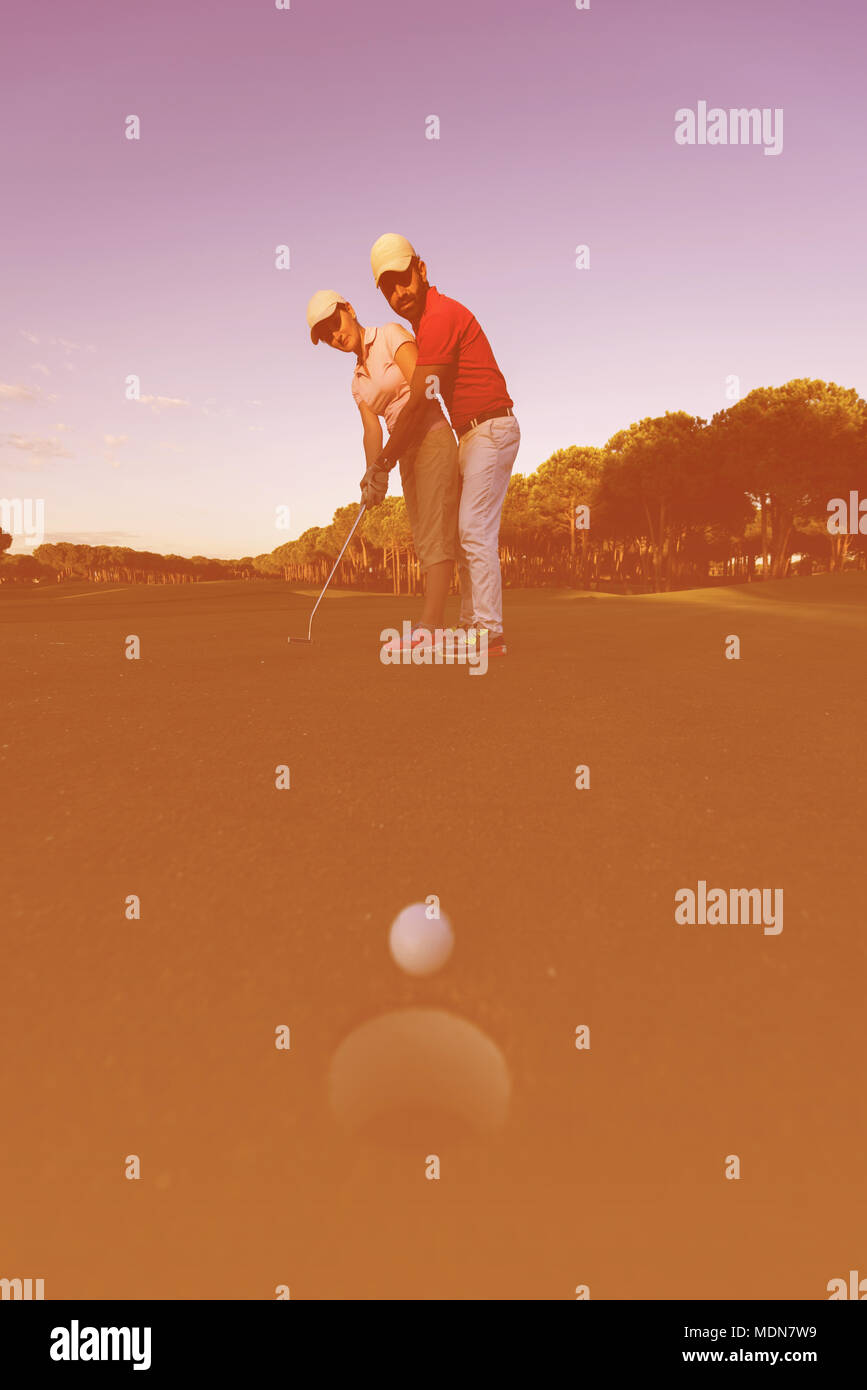 male golf instructor teaching female golf player, personal trainer giving lesson on golf course