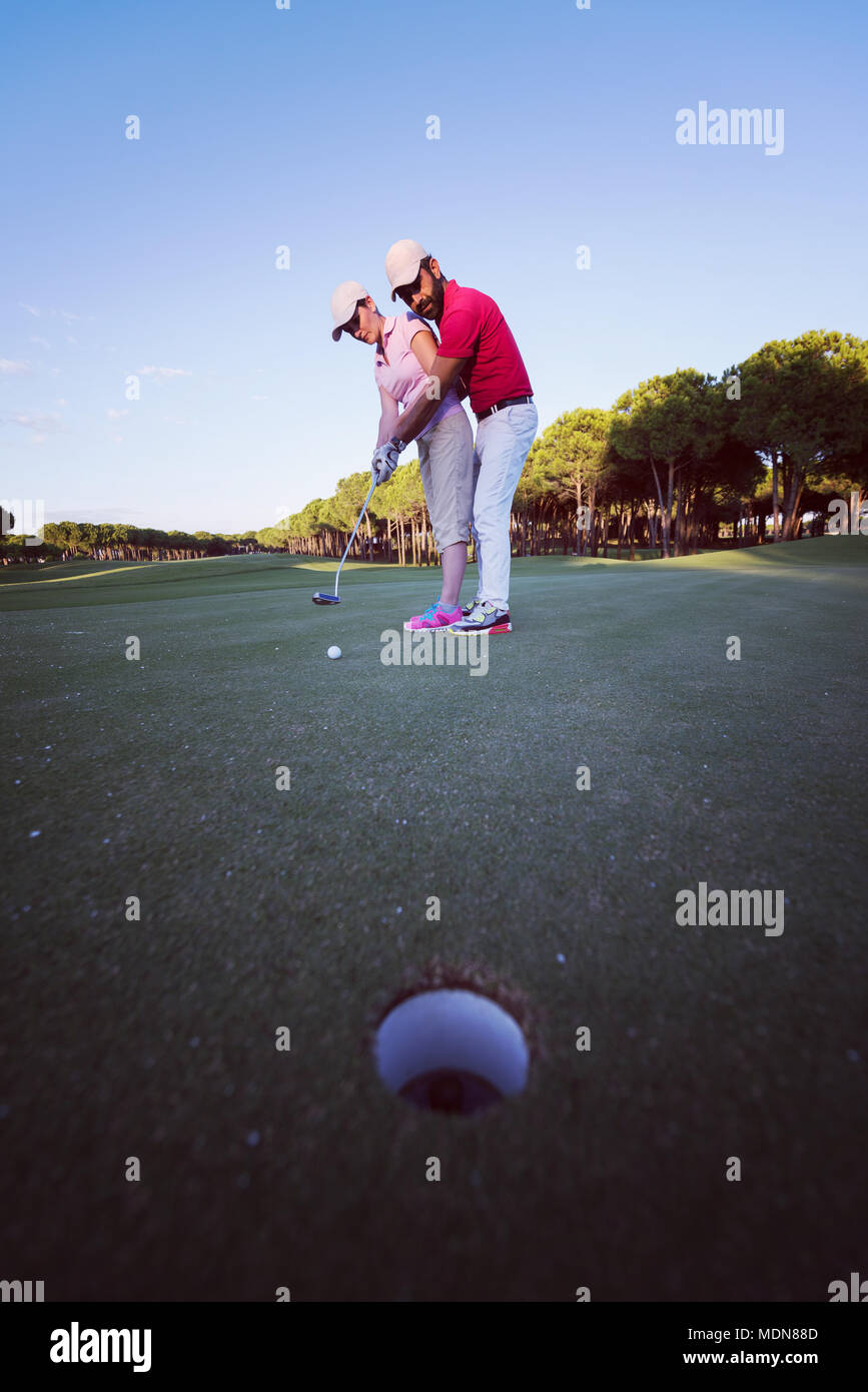 male golf instructor teaching female golf player, personal trainer