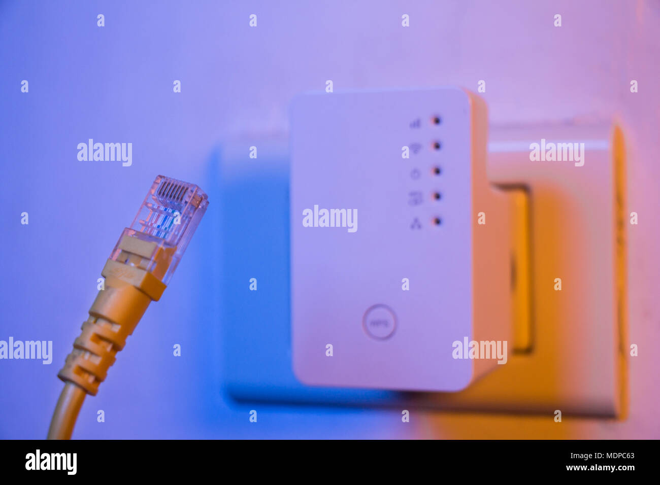 Closeup of cable. WiFi extender device in electrical socket on