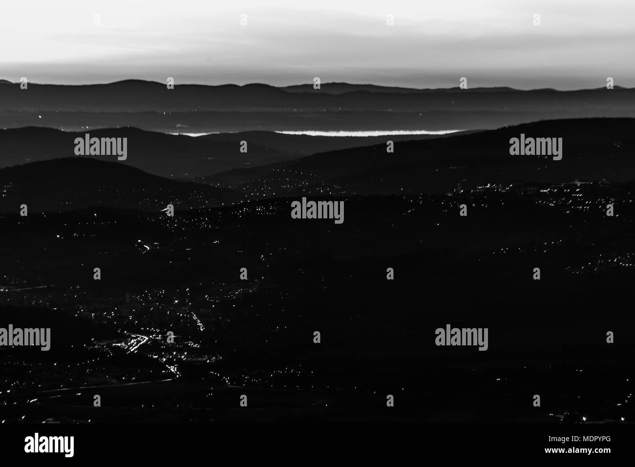 Beautiful aerial view of Umbria (Italy) valley at dusk, with hills, Perugia city lights and Trasimeno lake reflecting sky light Stock Photo