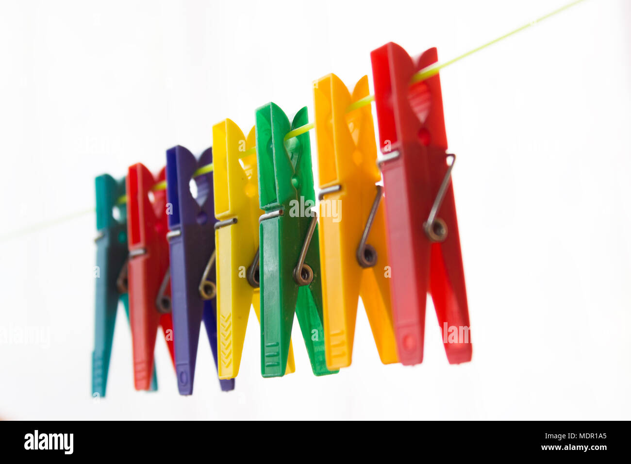 Colorful clothespins hanging on a clothesline. The background is white. Stock Photo