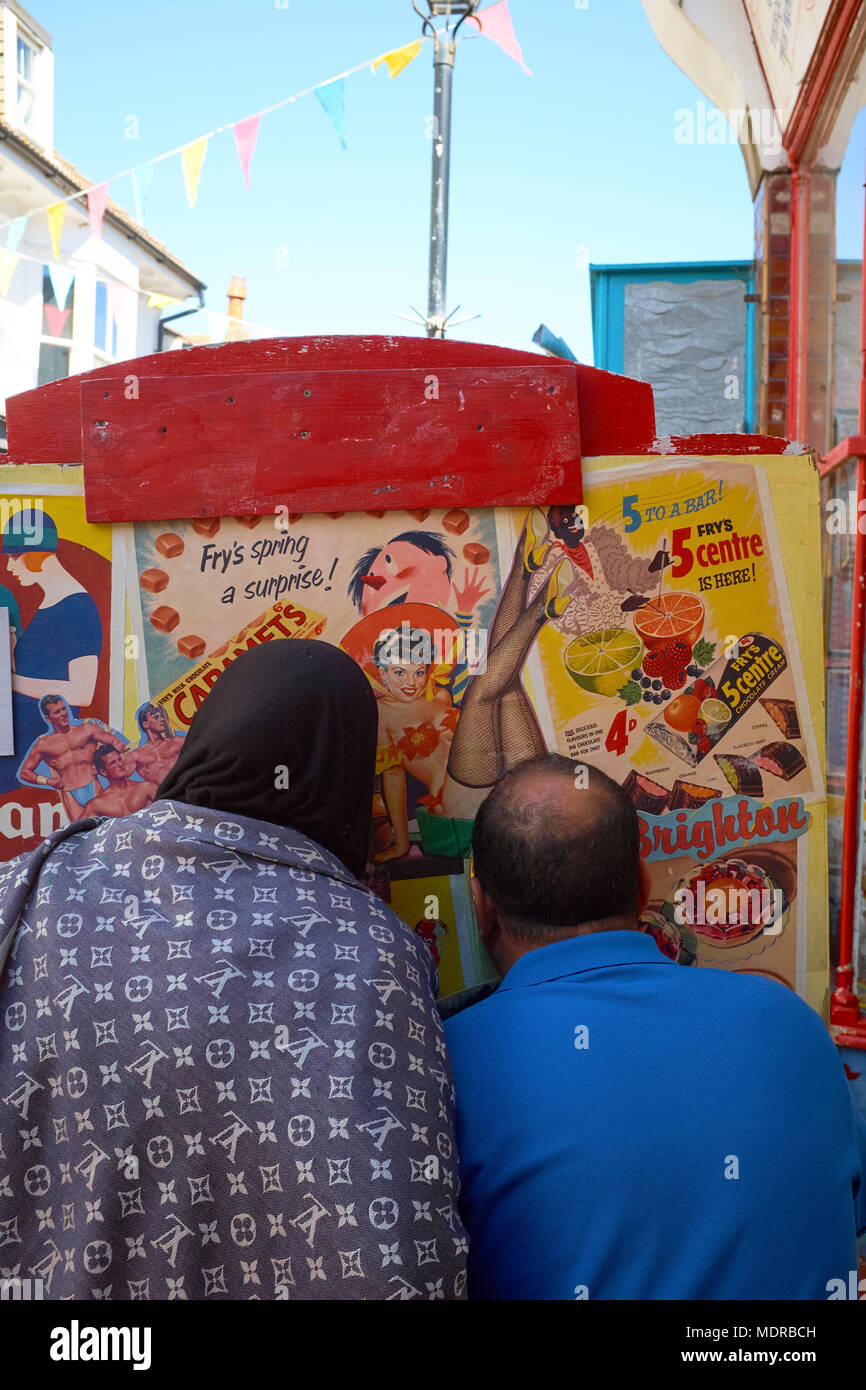 A Muslim couple having their picture taken using a comedy seaside cut out photo board - A captured moment on a summer day in Brighton England Stock Photo