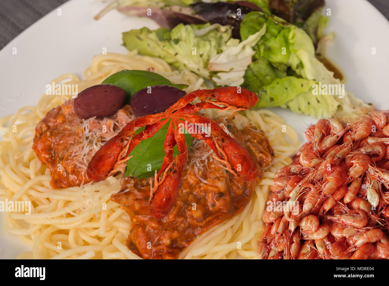 Spaghetti bolognese with basil leaf, lettuce red Spanish olives, prawns