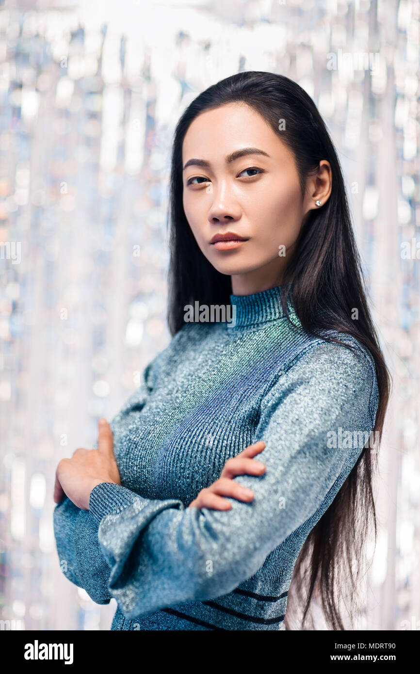 Confident asian woman in blue dress with crossed arms posing in studio ...