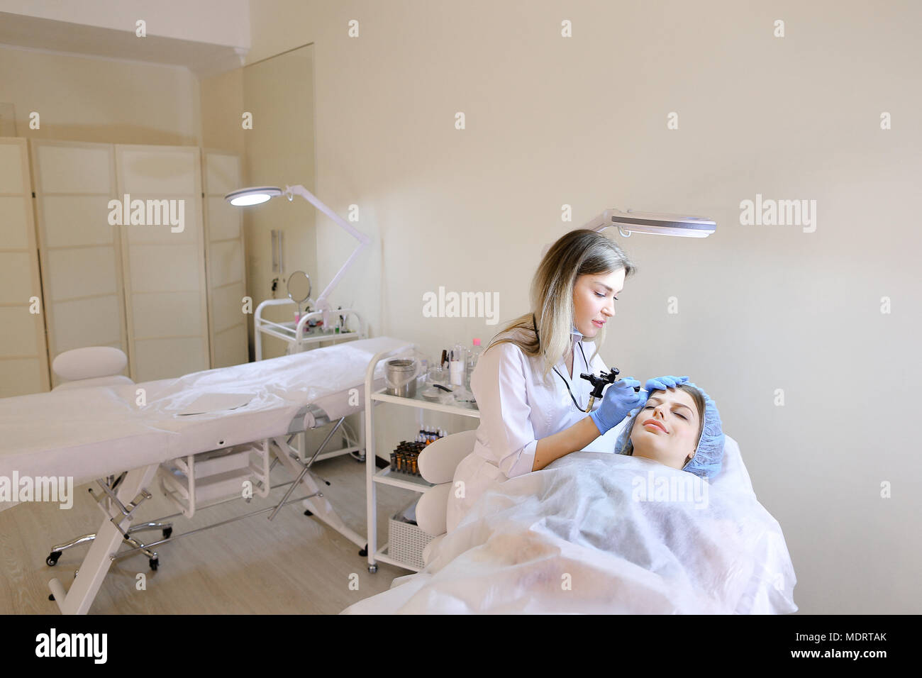 Female person at cosmetology getting tattooing eyebrows by