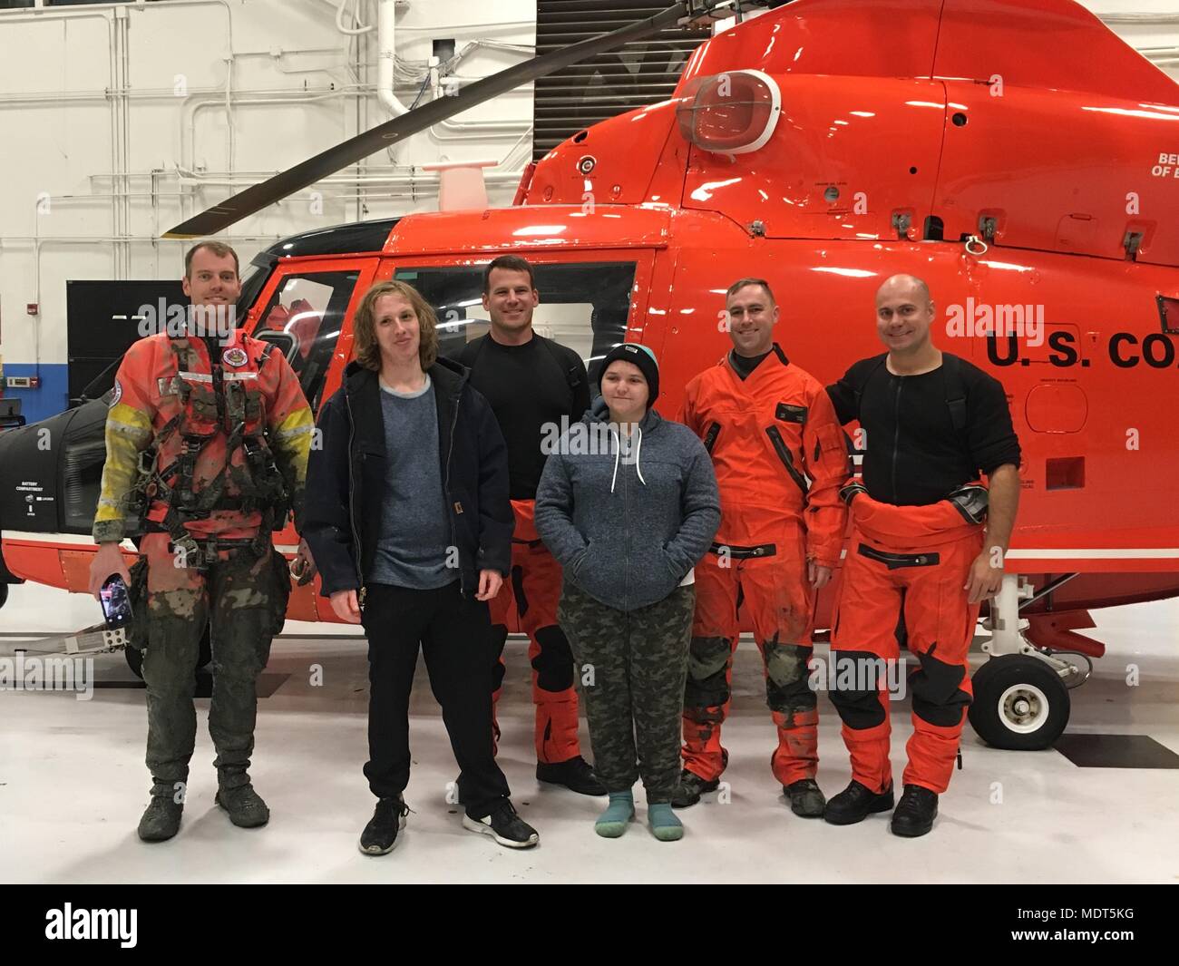 An MH-65 Dolphin helicopter crew from Coast Guard Air Station San Francisco stands for a photo with two boaters they rescued near Alviso, California, Dec. 3, 2017. The Coast Guard was called to assist when two of the three boaters requested to be removed from an aground boat due to concerns for hypothermia while the third person waited for high tide to refloat the boat. (U.S. Coast Guard photo) Stock Photo