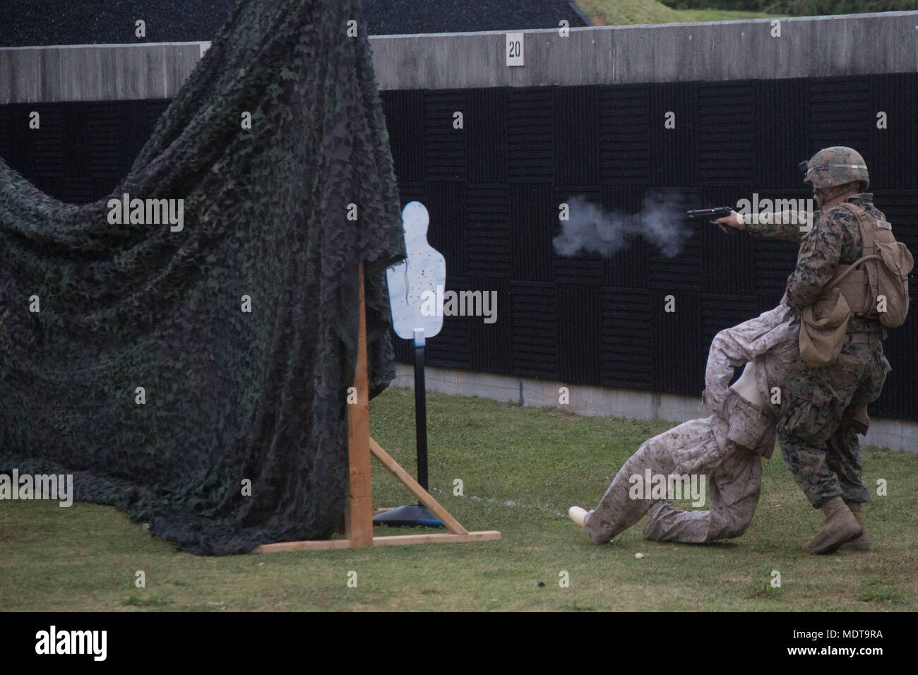 Beretta M9 is a 9×19mm semi automatic pistol adopted by the United States Armed Forces as a standard sidearm. The archival image documents a Marine firing the M9 during a live fire event at Camp Hansen Okinawa Japan on December 7 2017 within a squad competition. Stock Photo