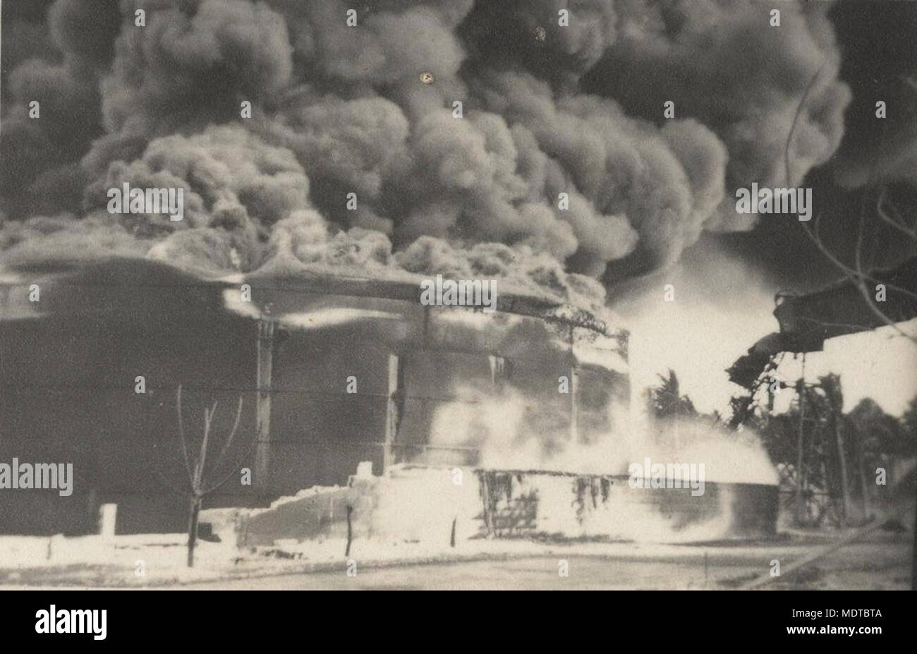 Oil tanks ablaze from damage by a German raider on. Location: Nauru     Description: The damage was caused by a German raider. Nauru was evacuated on 23/2/1942 and the Japanese occupied the island a few months later. Stock Photo