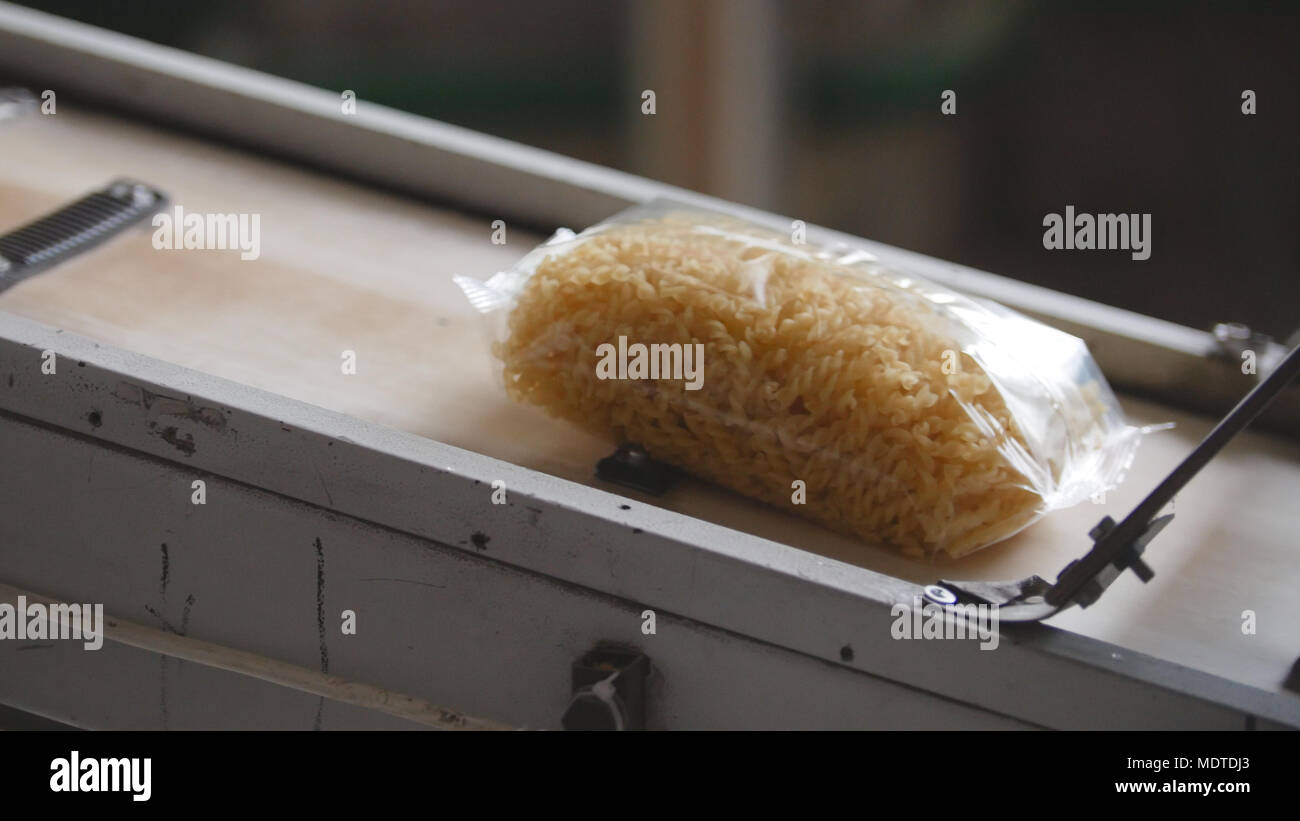 Food factory - conveyor with plastic pack of macaroni Stock Photo