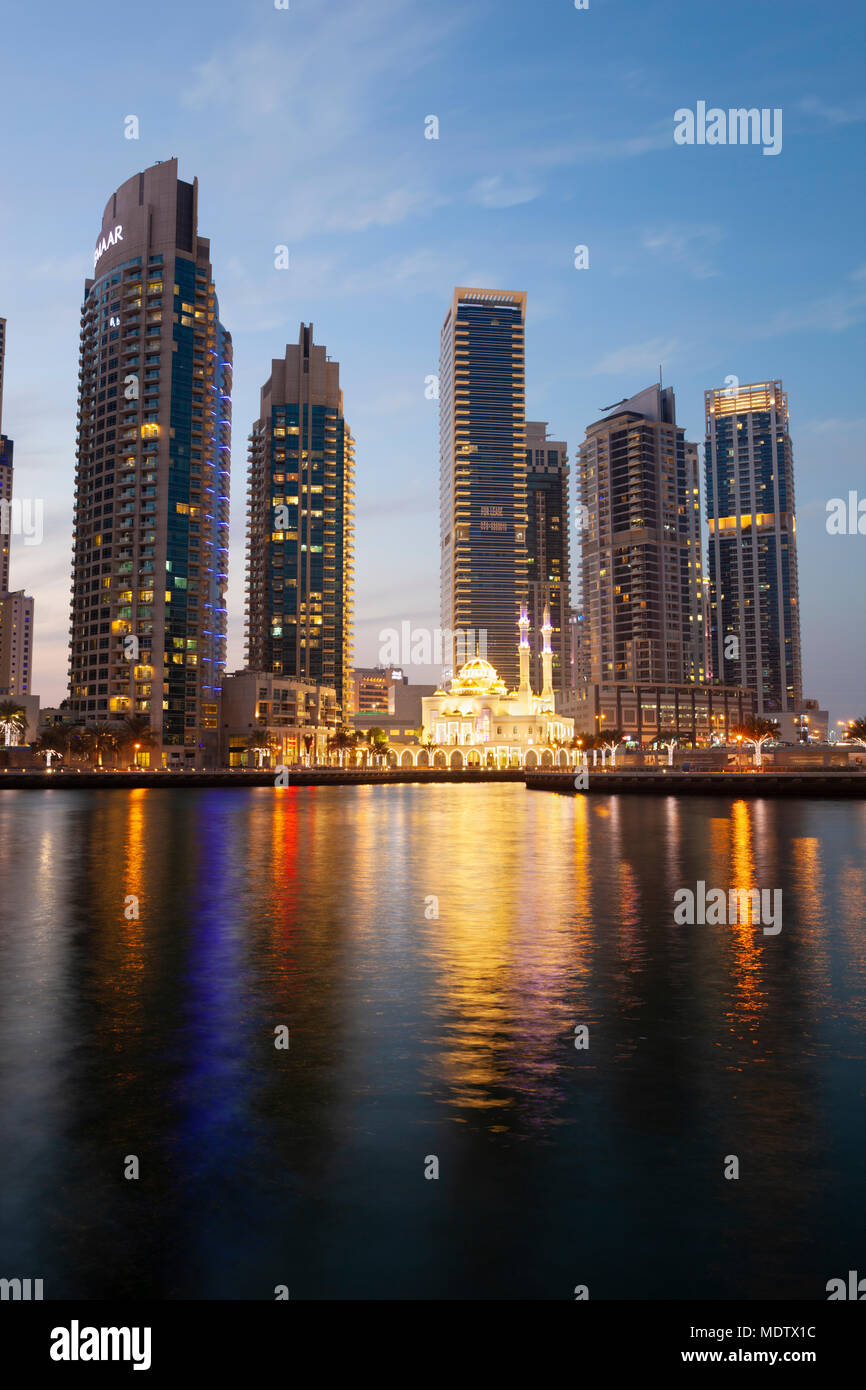 Floodlit mosque below modern architecture and towers reflected in water at the Dubai Marina, Dubai, United Arab Emirates, Middle East Stock Photo
