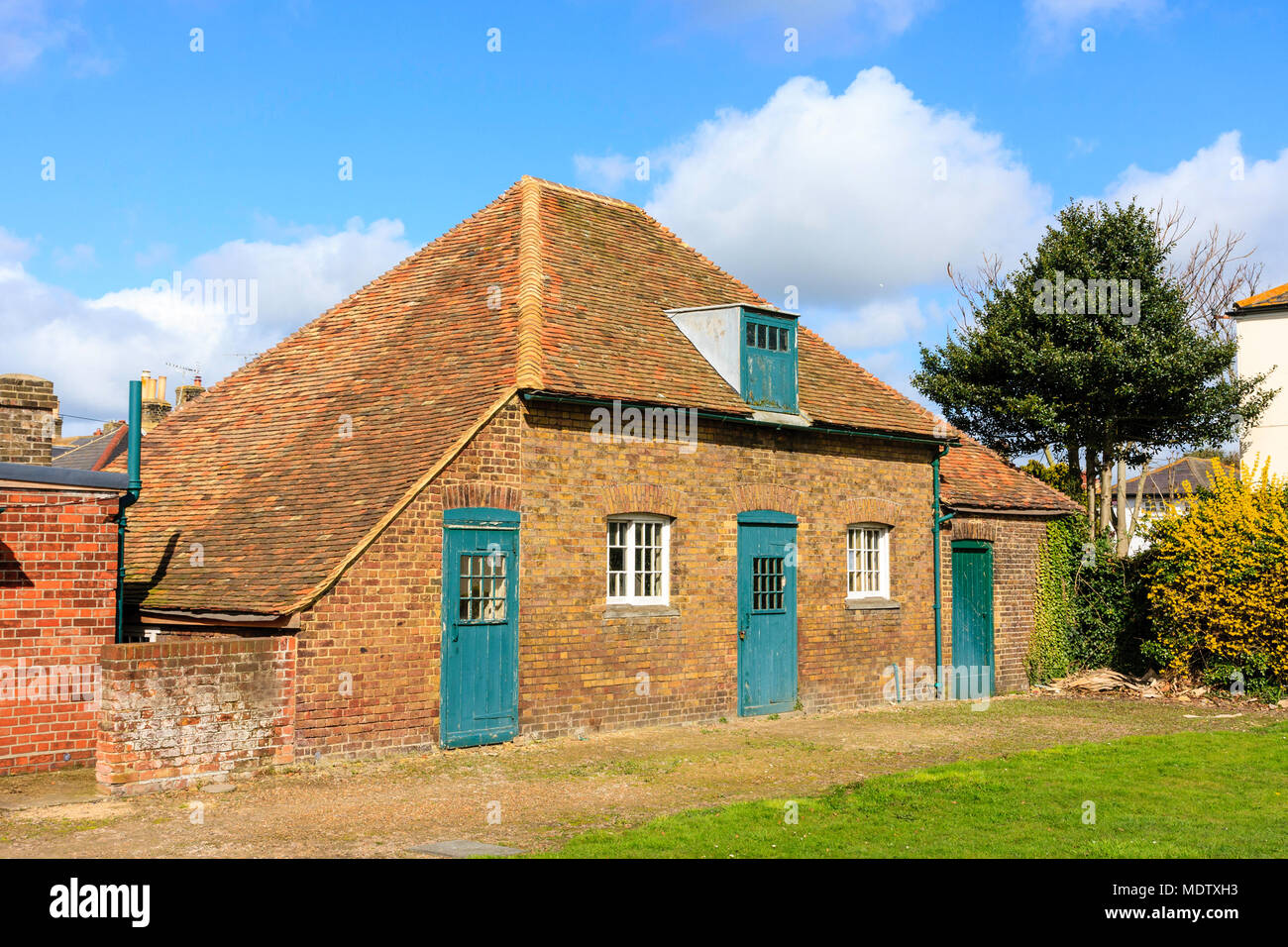 England, Deal castle. Napoleonic storehouse opposite the castle. Single storey building with attic window. Green doors. Daytime, blue skies. Stock Photo