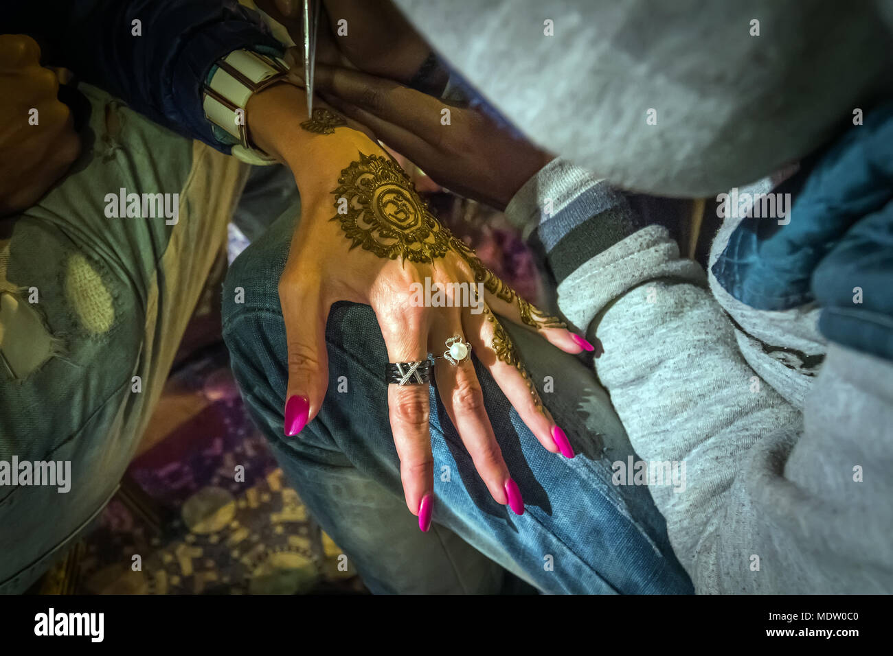 Artist drawing henna pattern on woman hand, a tradition art