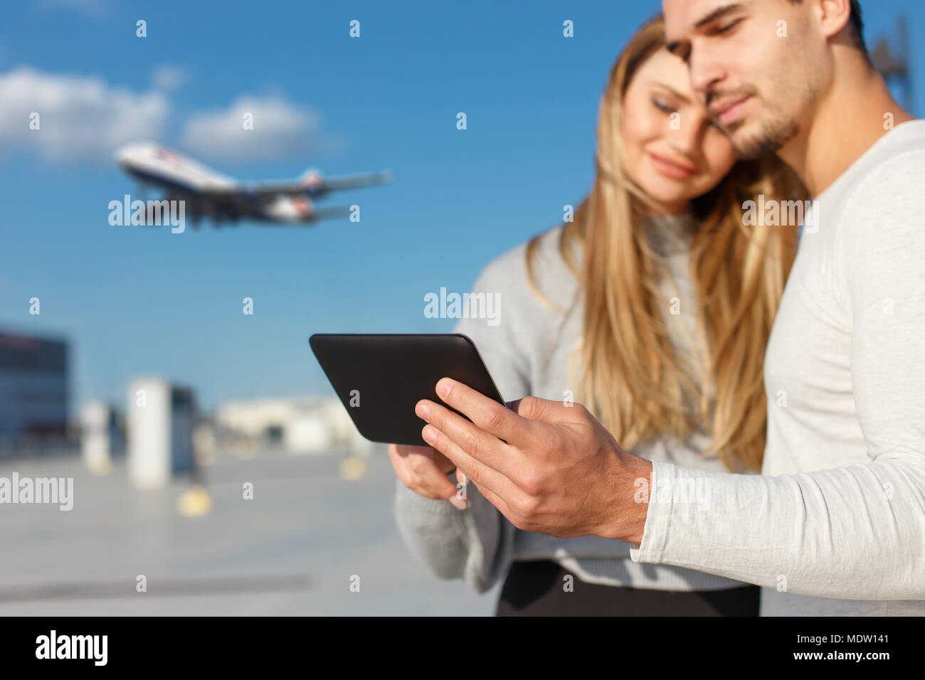 Young couple booing flight on digital tablet outdoor, buying air ticket Stock Photo