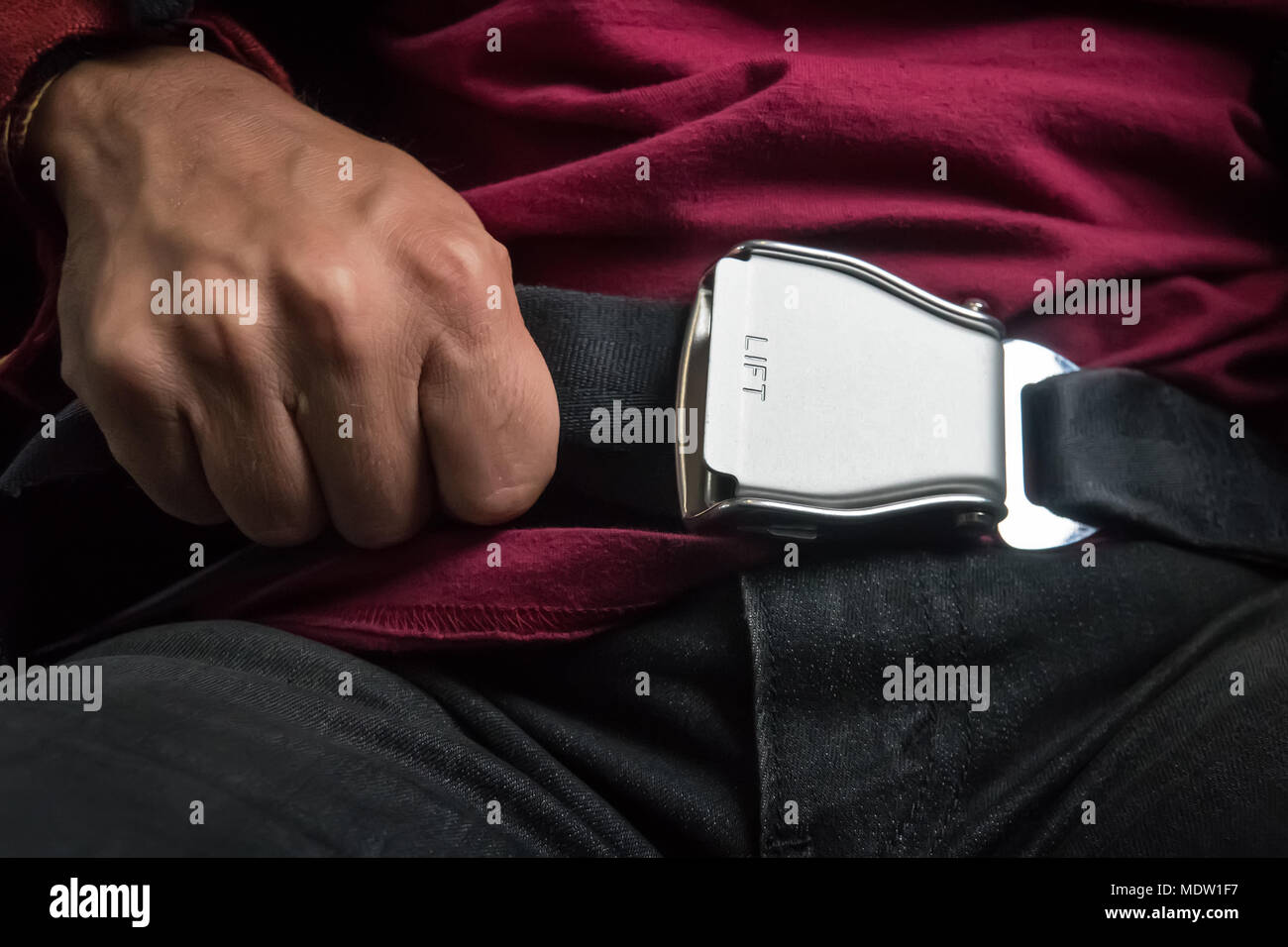 Closeup of a safety belt in the airplane. male hand tightens the