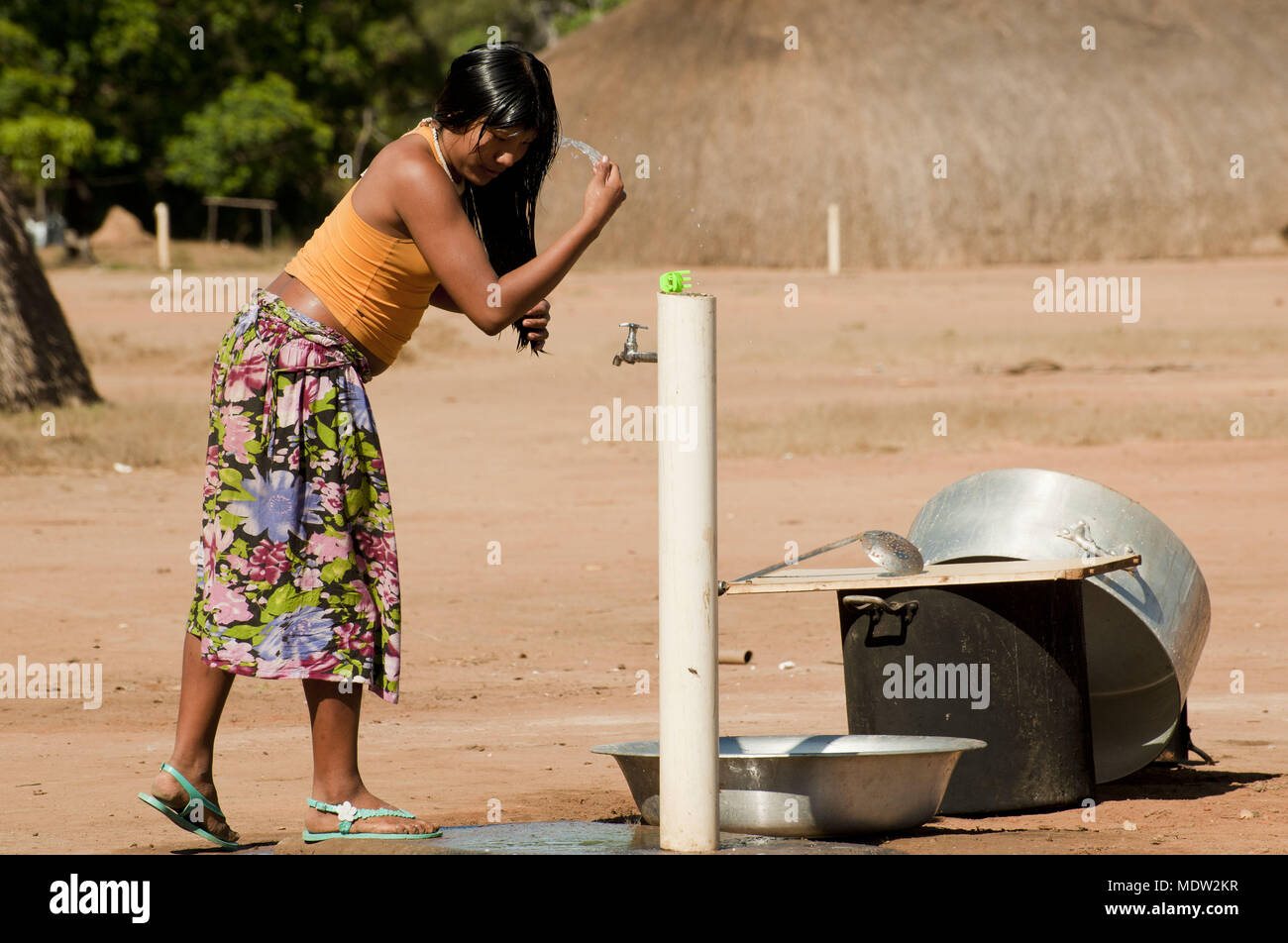 india teen ethnicity Kalapalo washing hair on tap in front of the hollow - Village Aiha Stock Photo