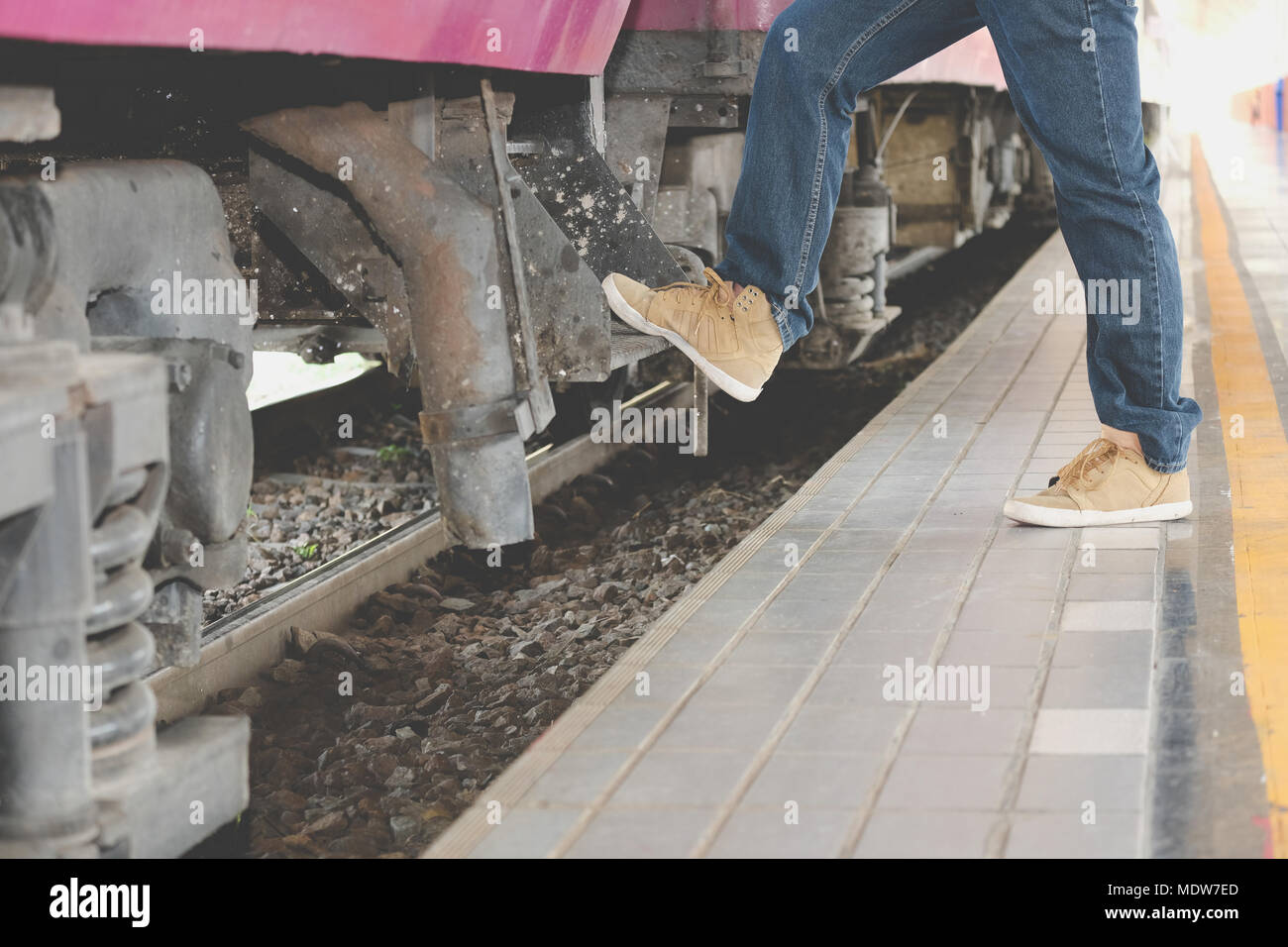 man traveler stepping up train at railway station. male backpacker travel alone. Journey on holiday Stock Photo