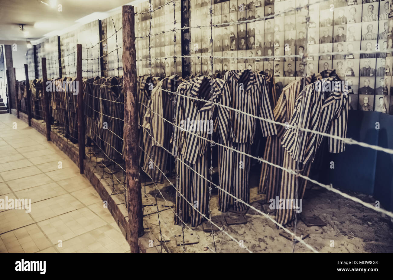 Oswiecim / Poland - 02.15.2018: Auschwitz Museum Exhibition with prisoners' clothes with stripes behind a barbed wire fence. Stock Photo