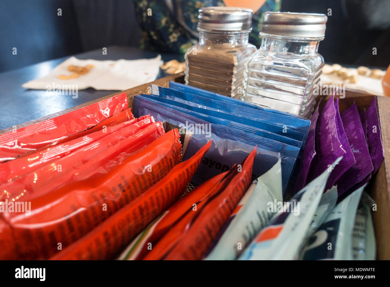 Salt, pepper and sachets of sauce in a tray on a table. Stock Photo