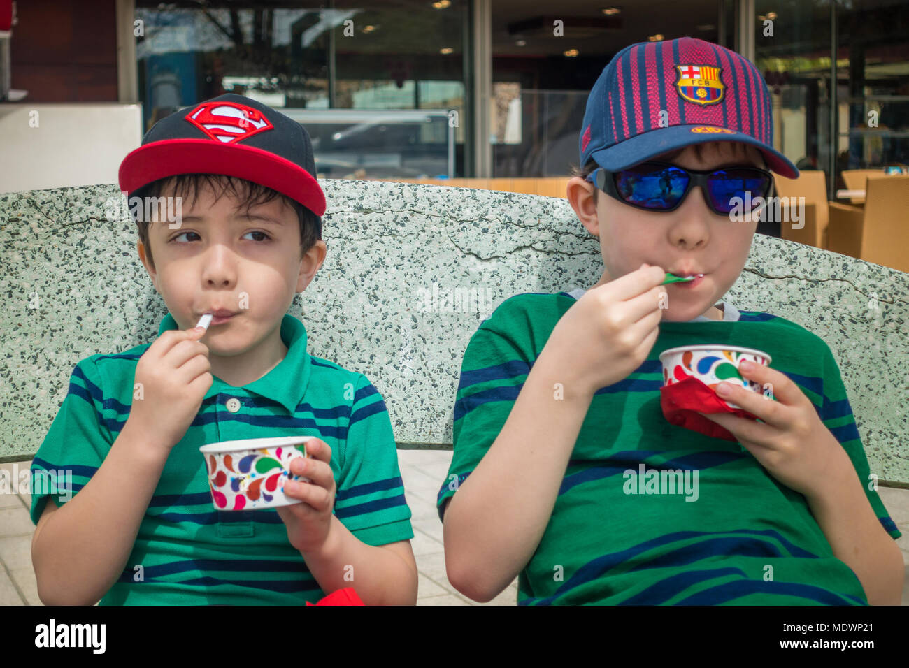 Young boys sit together eating tubs of ice cream Stock Photo