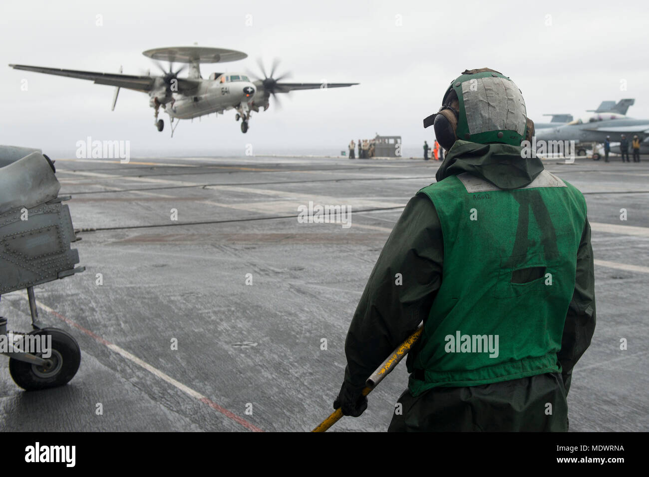 171208-N-PE636-079 ATLANTIC OCEAN (Dec. 8, 2017) Aviation Boatswain's Mate (Equipment) Airman Brandon Chapman watches an E-2C Hawkeye, assigned to the 'Greyhawks' of Carrier Airborne Early Warning Squadron (VAW) 120, prepare to land on the flight deck aboard USS Harry S. Truman (CVN 75). Truman is currently underway conducting carrier qualifications in preparation for future operations. (U.S. Navy photo by Mass Communication Specialist 2nd Class Anthony Flynn/Released) Stock Photo