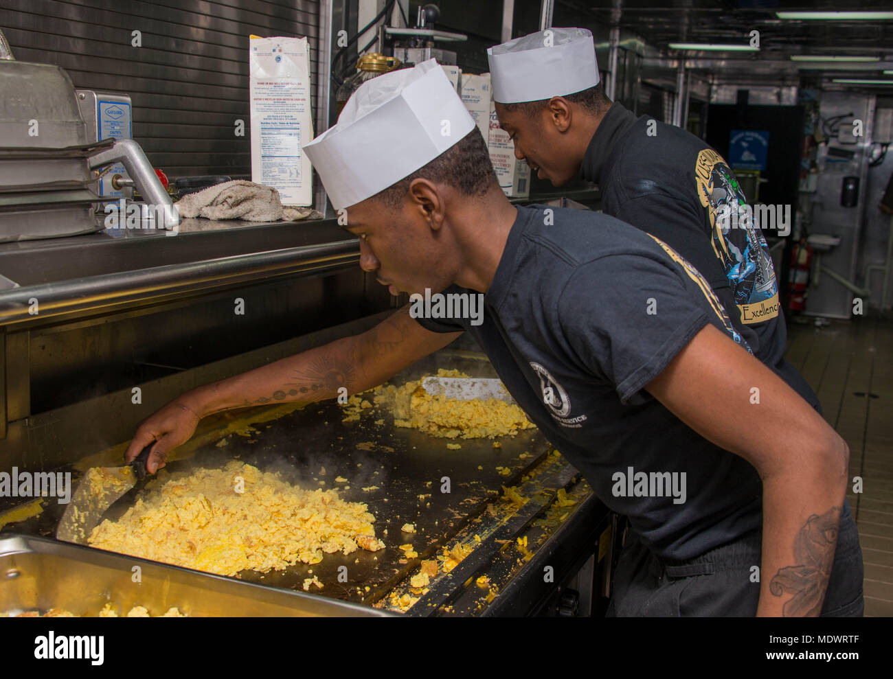 ATLANTIC OCEAN (Dec. 9, 2017) Culinary Specialist Seaman Raekwon Barksdale, front, from Houston, Texas and Culinary Specialist Seaman Apprentice Dante Herron, rear, from Detroit, Michigan prepare scrambled eggs on the grill in the galley of the amphibious assault ship USS Iwo Jima (LHD 7). Iwo Jima, components of the Iwo Jima Amphibious Ready Group and the 26th MEU are conducting a Combined Composite Training Unit Exercise that is the culmination of training for the Navy-Marine Corps team and will certify them for deployment. (U.S. Navy photo by Mass Communication Specialist 3rd Class Kevin Le Stock Photo