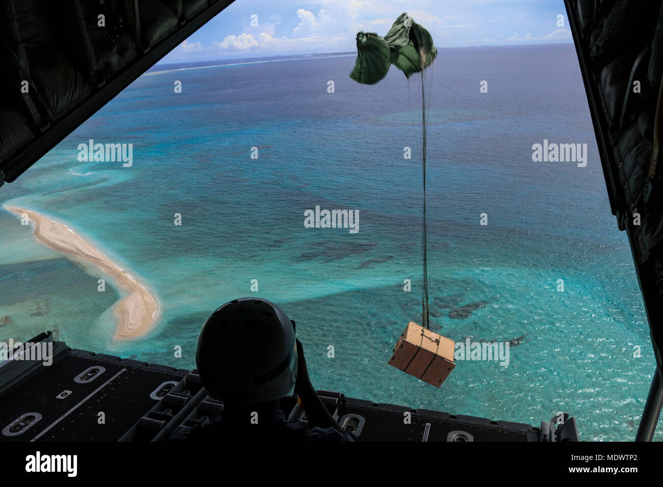 Royal Australian Air Force Leading Aircraftman Stephen Manila, 37th Squadron Avionics Technician, watches a bundle depart a RAAF C-130J Super Hercules and fall toward a Micronesian island during the 66th Operation Christmas Drop Dec. 10, 2017. Members of OCD built 120 bundles in order to provide essential supplies to people on 56 different Micronesian islands. (U.S. Air Force photo by Staff Sgt. David Owsianka) Stock Photo