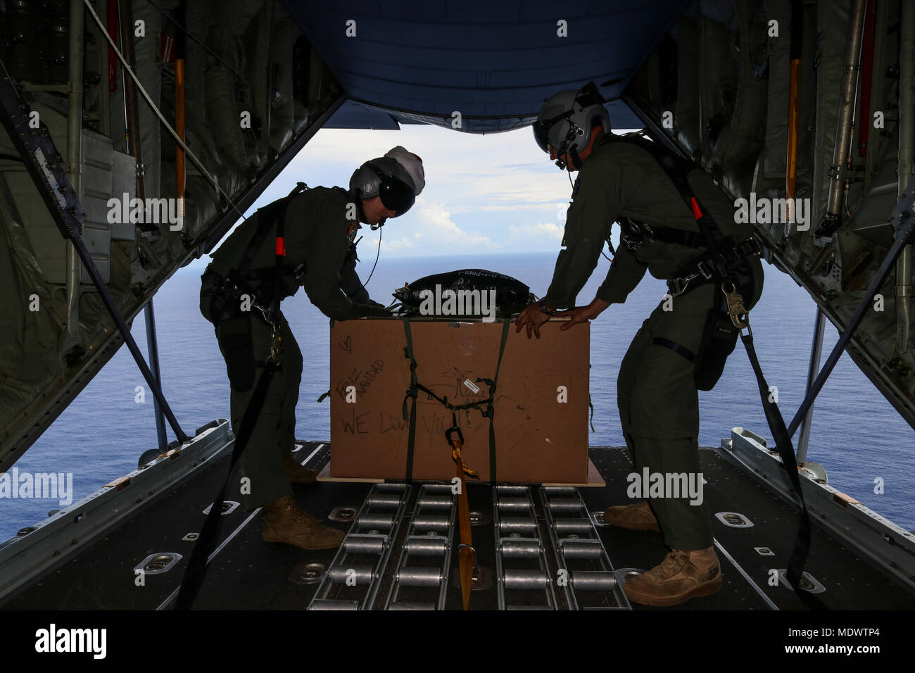 Royal Australian Air Force Sergeant Karl Penny, left, and Warrant Officer Nicholas Stubbs-Race, both 37th Squadron loadmasters, prepare to release a bundle during the 66th Operation Christmas Drop, Dec. 10, 2017. The aircrews airdropped food, supplies and educational materials to islanders throughout the Commonwealth of the Northern Marianas, Federated States of Micronesia, and Republic of Palau. These islands are some of the most remote locations on the globe spanning a distance nearly as broad as the continental US. (U.S. Air Force photo by Staff Sgt. David Owsianka) Stock Photo