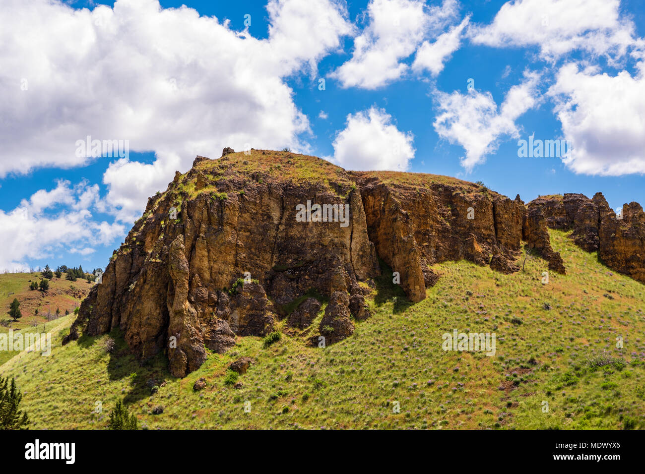 https://c8.alamy.com/comp/MDWYX6/sharp-rock-cliffs-on-a-bed-of-soft-grass-blue-sky-and-clouds-above-MDWYX6.jpg
