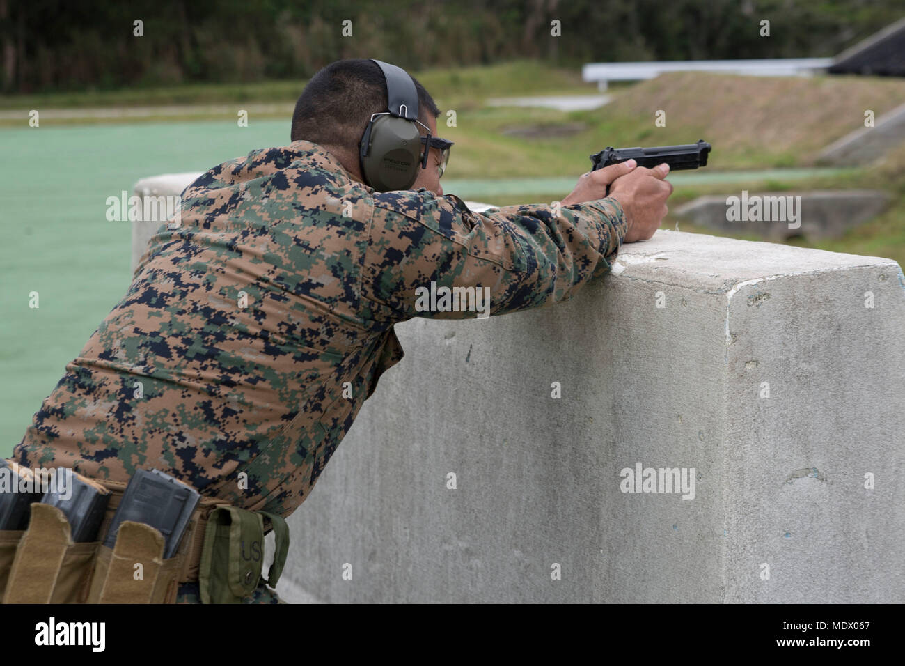 Gunnery Sgt. Don Mendiola, the spectrum manager with the 31st Marine Expeditionary Unit, prepares to fire an M9 service pistol during the Far East Annual Marksmanship Competition at Camp Hansen, Okinawa, Japan, Dec. 8, 2017. The competition helps improve the marksmanship, proficiency and combat readiness of the participants and is the first step toward the Marine Corps Championship in Quantico, Virginia. Competitors from the Far East, Pacific, East and West come together for the championship to learn more about marksmanship and the chance to be recruited to the Marine Corps Shooting Team. As t Stock Photo
