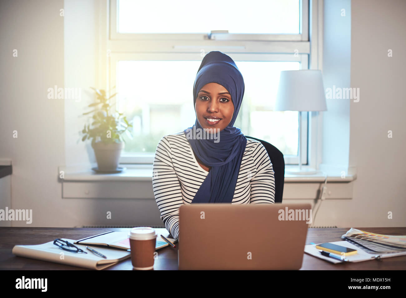 Young Arabic female entrepreneur wearing a hijab smiling confidently ...