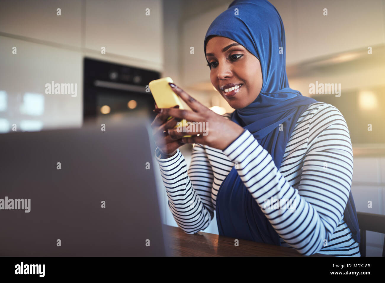 Smiling young Arabic female entrepreneur wearing a hijab sitting in her ...