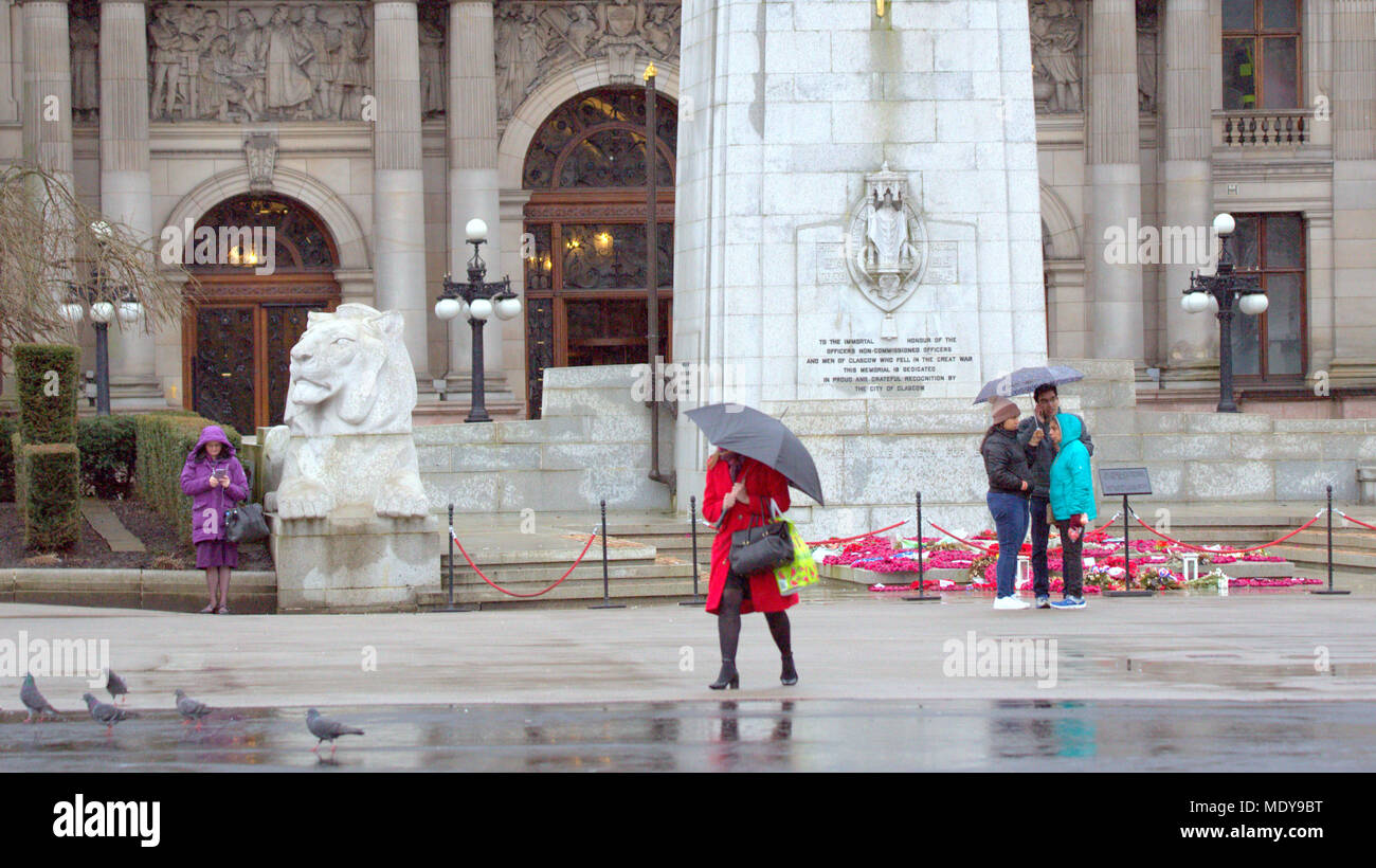 wet and rainy cenotaph war memorial red coat umbrella locals and tourists  in front of city chambers George Square, Glasgow, UK Stock Photo