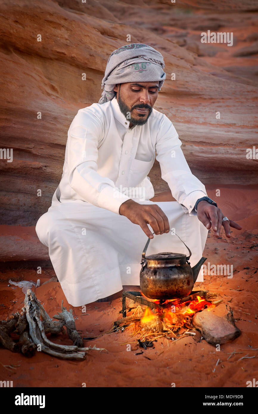 Young Bedouin man prepare traditional tea on the fire, Wadi Rum Desert, Jordan Stock Photo