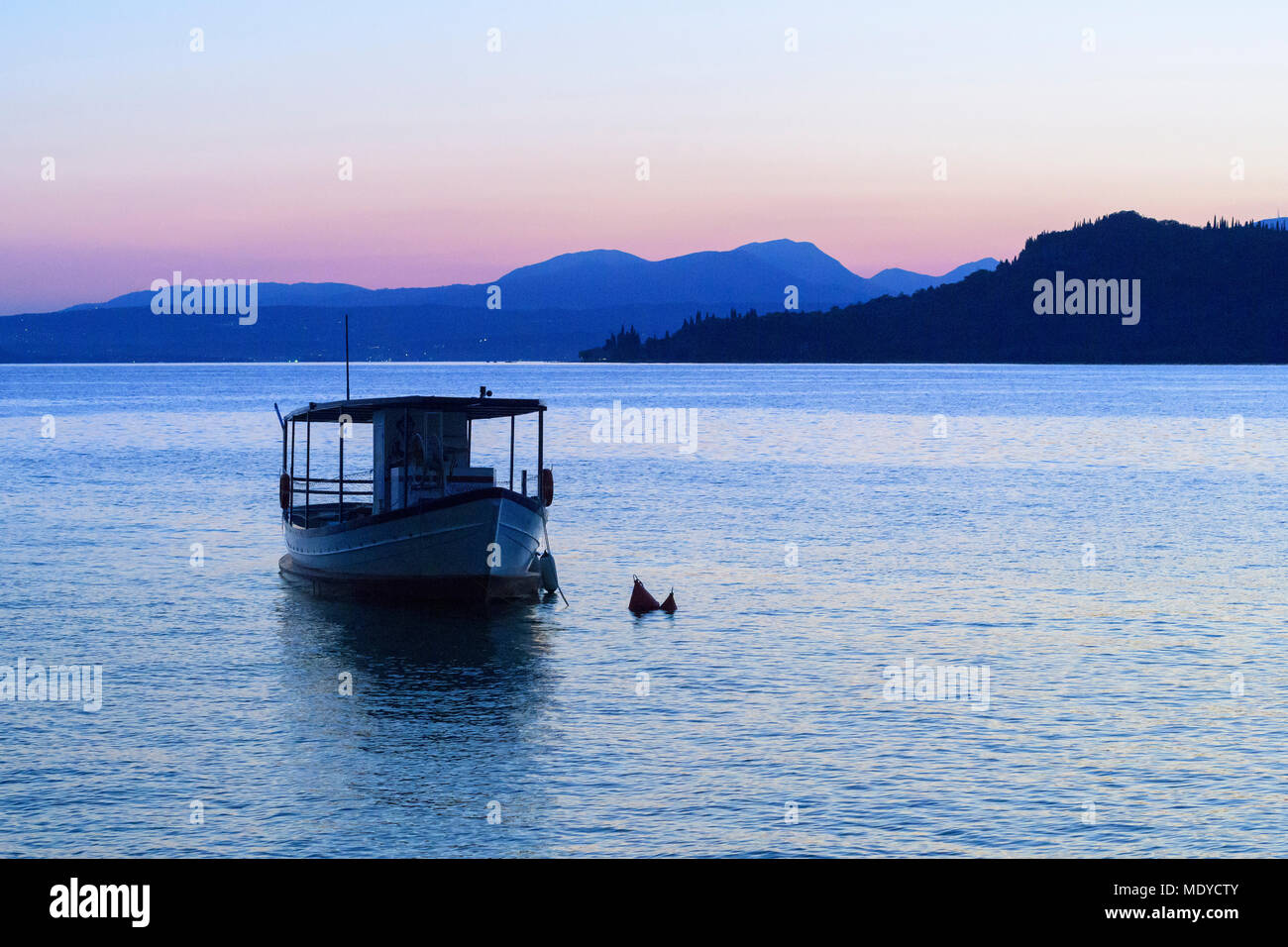 Silhouette of boat on Lake Garda (Lago di Garda) at dusk in Garda in Veneto, Italy Stock Photo