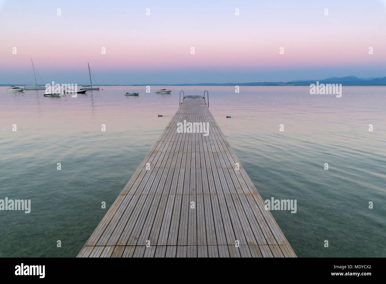 Wooden jetty on the Lake Garda (Lago di Garda) at dawn in Garda in Veneto, Italy Stock Photo