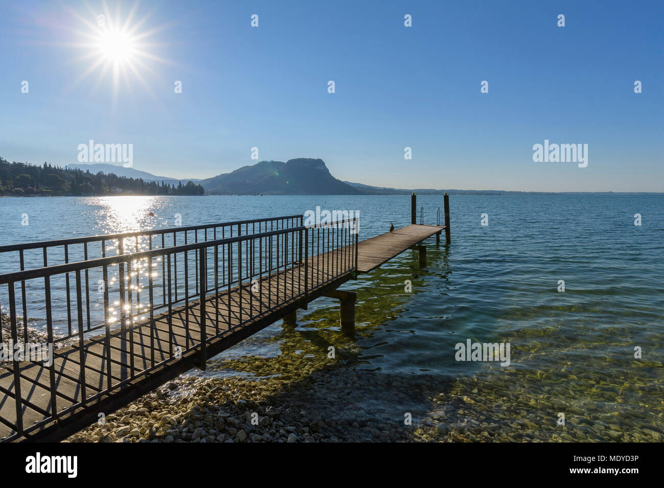 Sun shining on Lake Garda (Lago di Gardo) with wooden jetty in the summer at Garda in Veneto, Italy Stock Photo