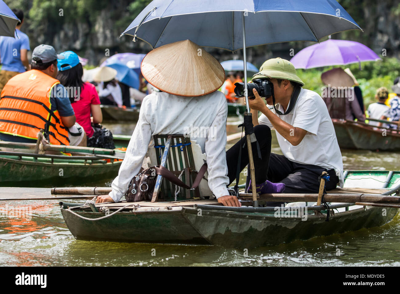 Photographer in a boat on the Ngo Dong River; Tam Coc, Ninh Binh, Vietnam Stock Photo