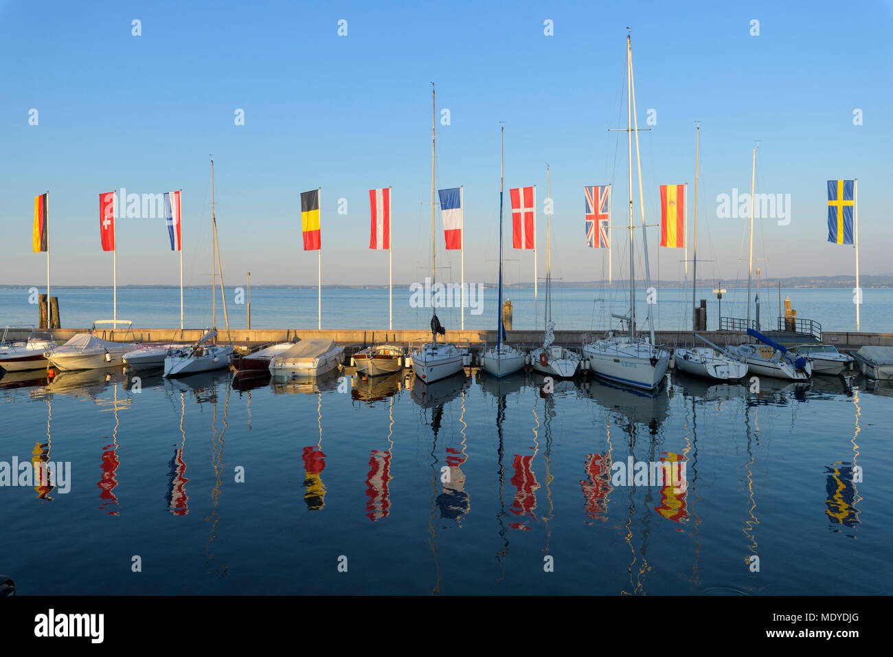 Row of boats and colorful European flags in the harbor marina on Lake Garda (Lago di Garda) at Bardolino in Veneto, Italy Stock Photo